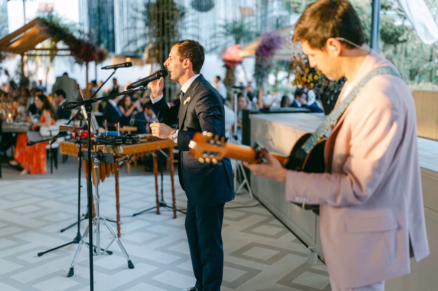 Musicians perform at an outdoor wedding reception with instruments and microphones.
