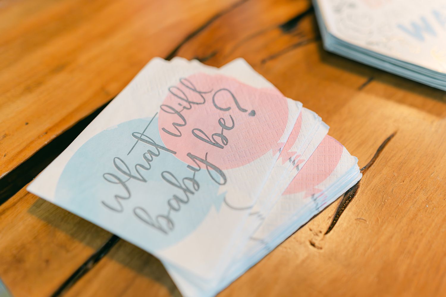 What will baby be gender reveal party napkins on wooden table at baby shower.