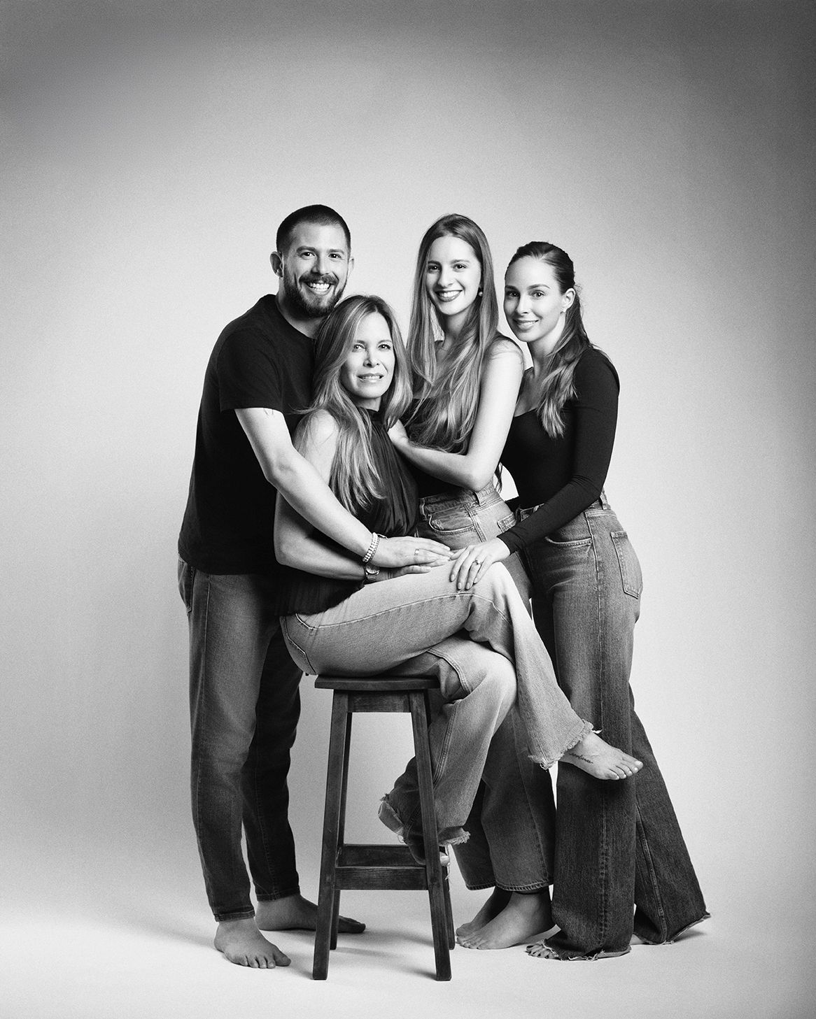 Black and white family portrait of four people posing together in a studio.