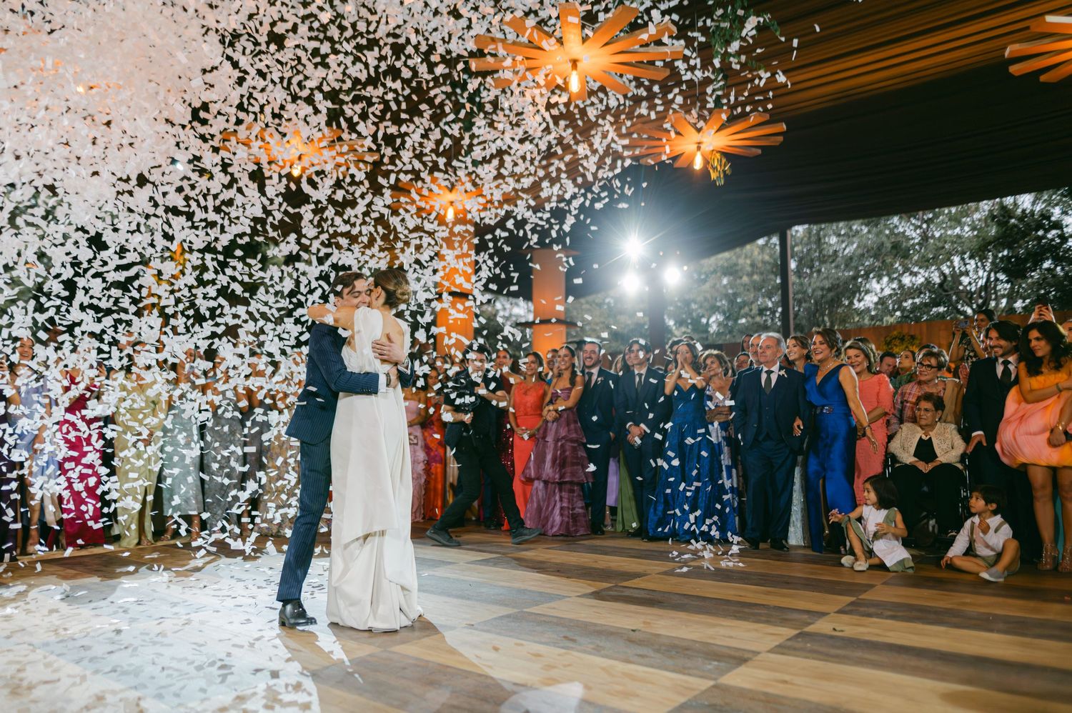 Bride and groom share first dance as confetti fills the air at their stunning wedding reception.