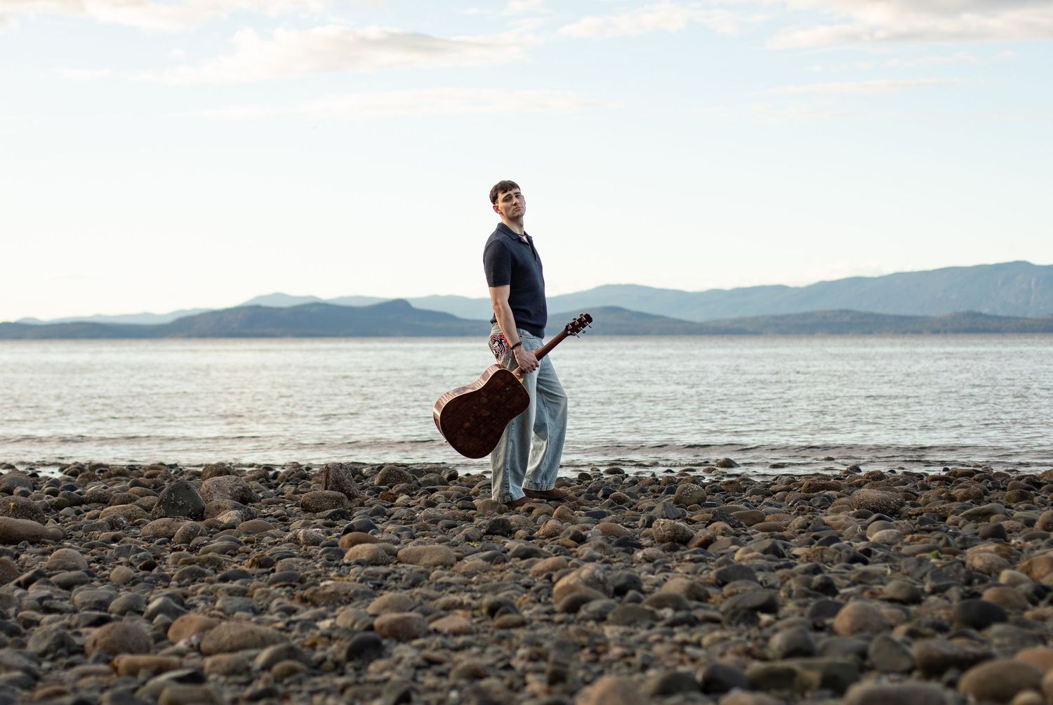 Portrait of a man with a guitar on the beach in Parksville, Vancouver Island, BC.