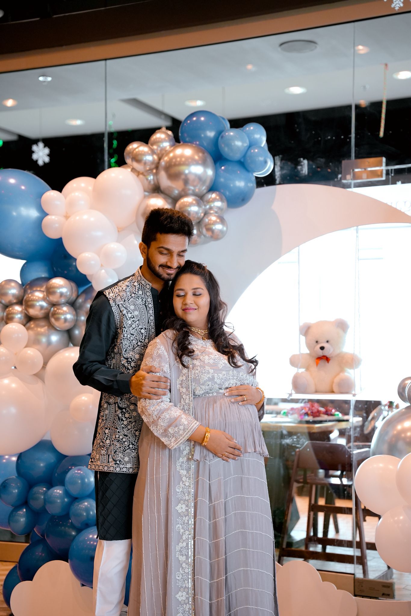 Baby shower celebration with pink and blue balloon decorations and elegant white dresses.