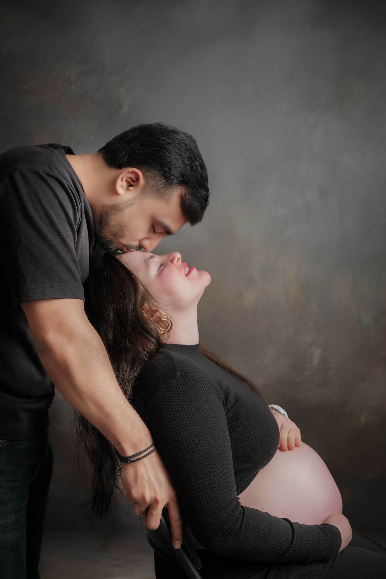 Dramatic maternity photoshoot featuring tender moments between couple.