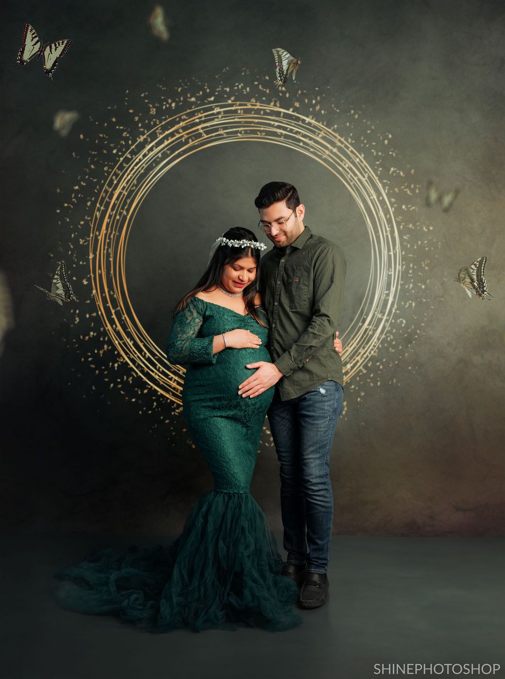 Artistic maternity portrait with circular gold frame and butterflies against dark dramatic background.