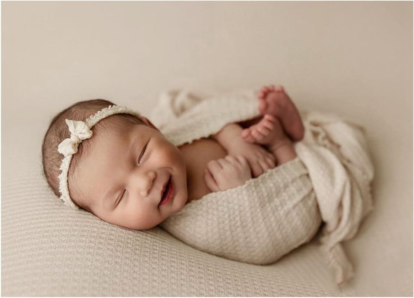 Peaceful newborn photography with baby wrapped in cream textured blanket.