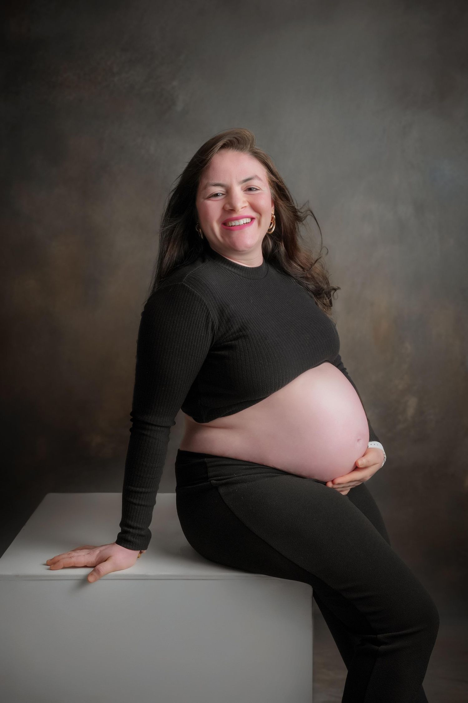 Maternity photography session shows joyful moments on white platform.