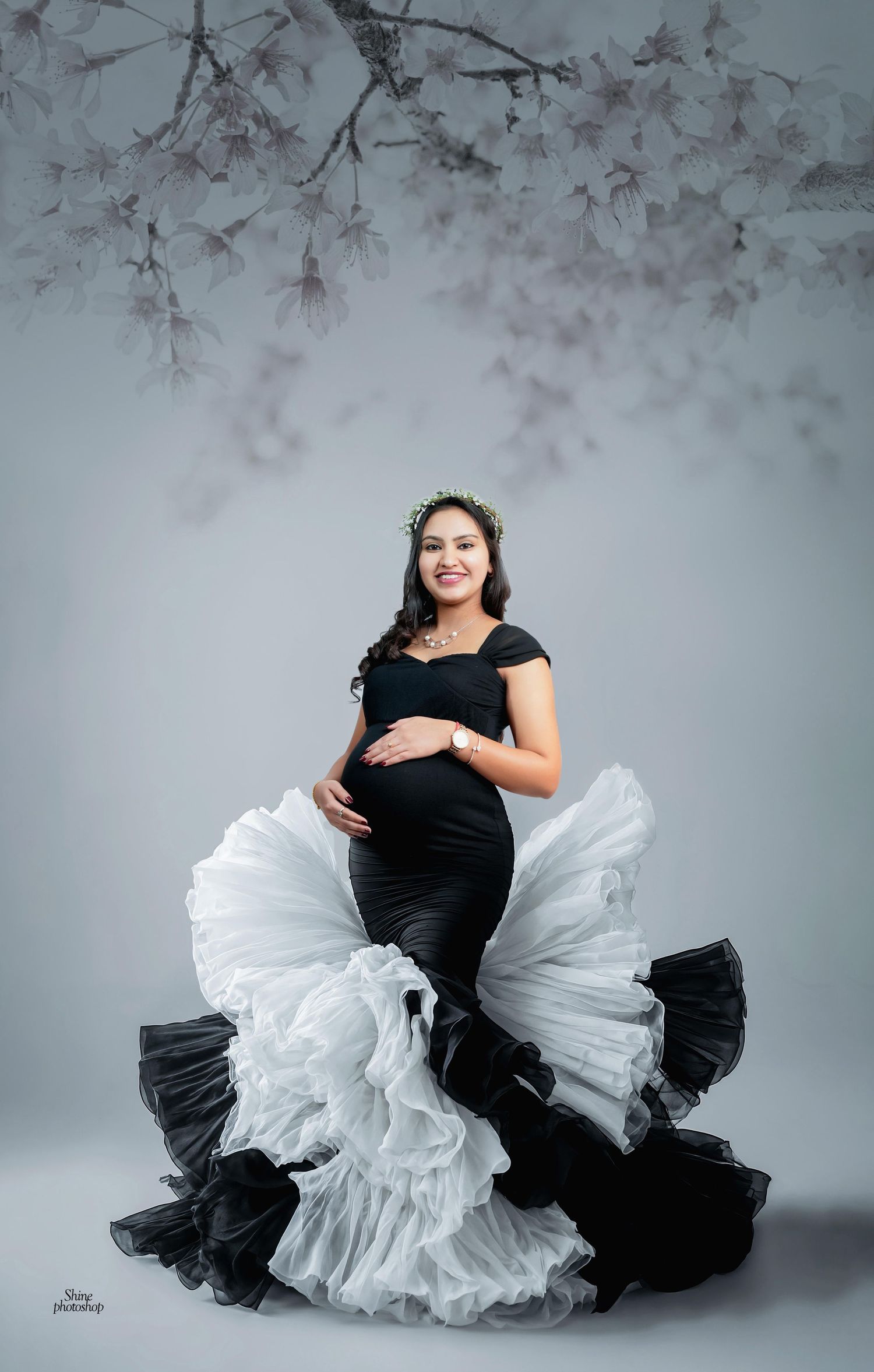 Elegant maternity photos featuring a black and white ruffled dress against a soft gray background.