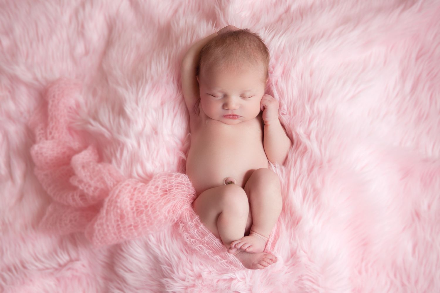 Delicate pink tulle fabric creates a dreamy backdrop for newborn photography session.