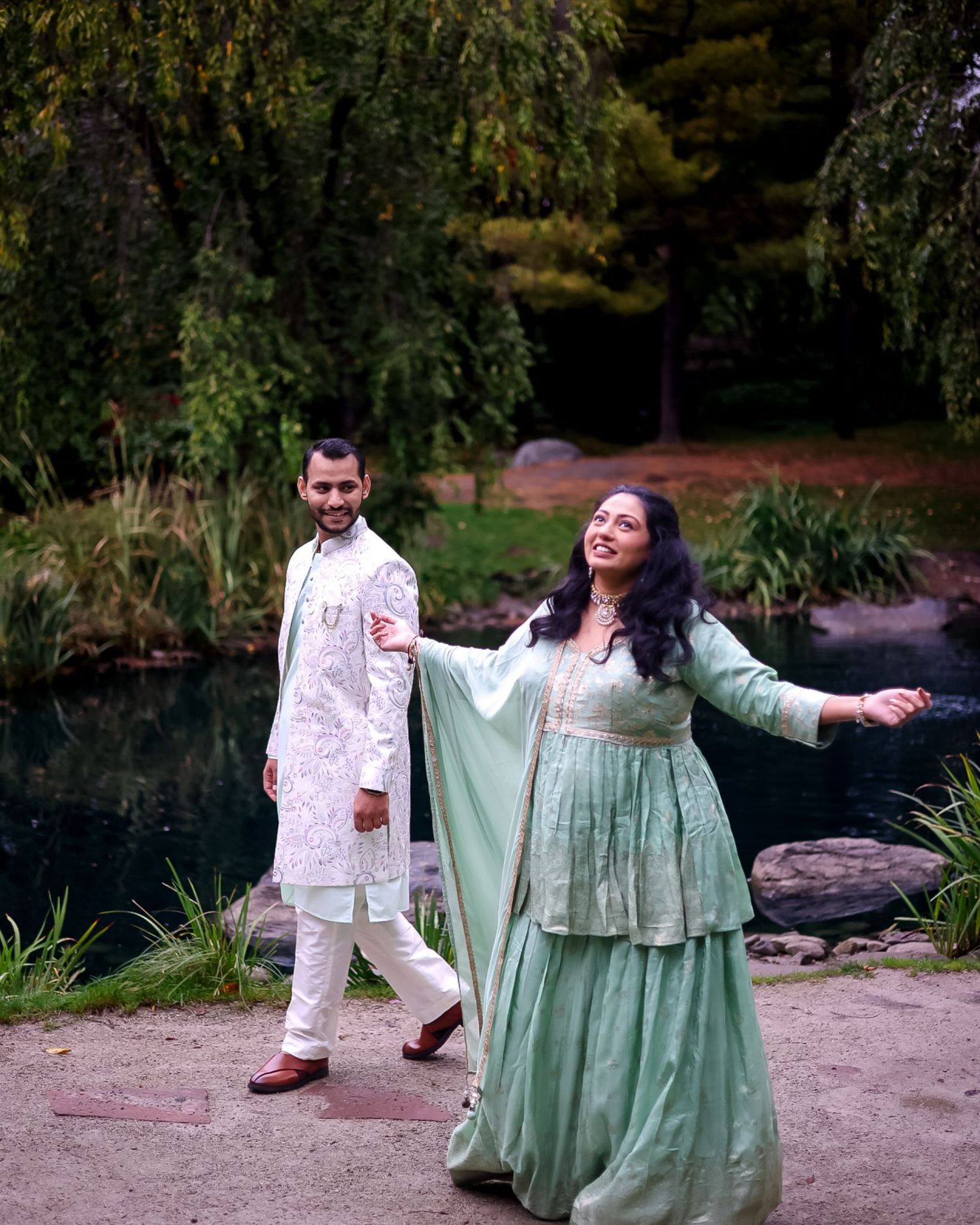 Outdoor maternity photoshoot with couple in white and mint green outfits by lakeside.