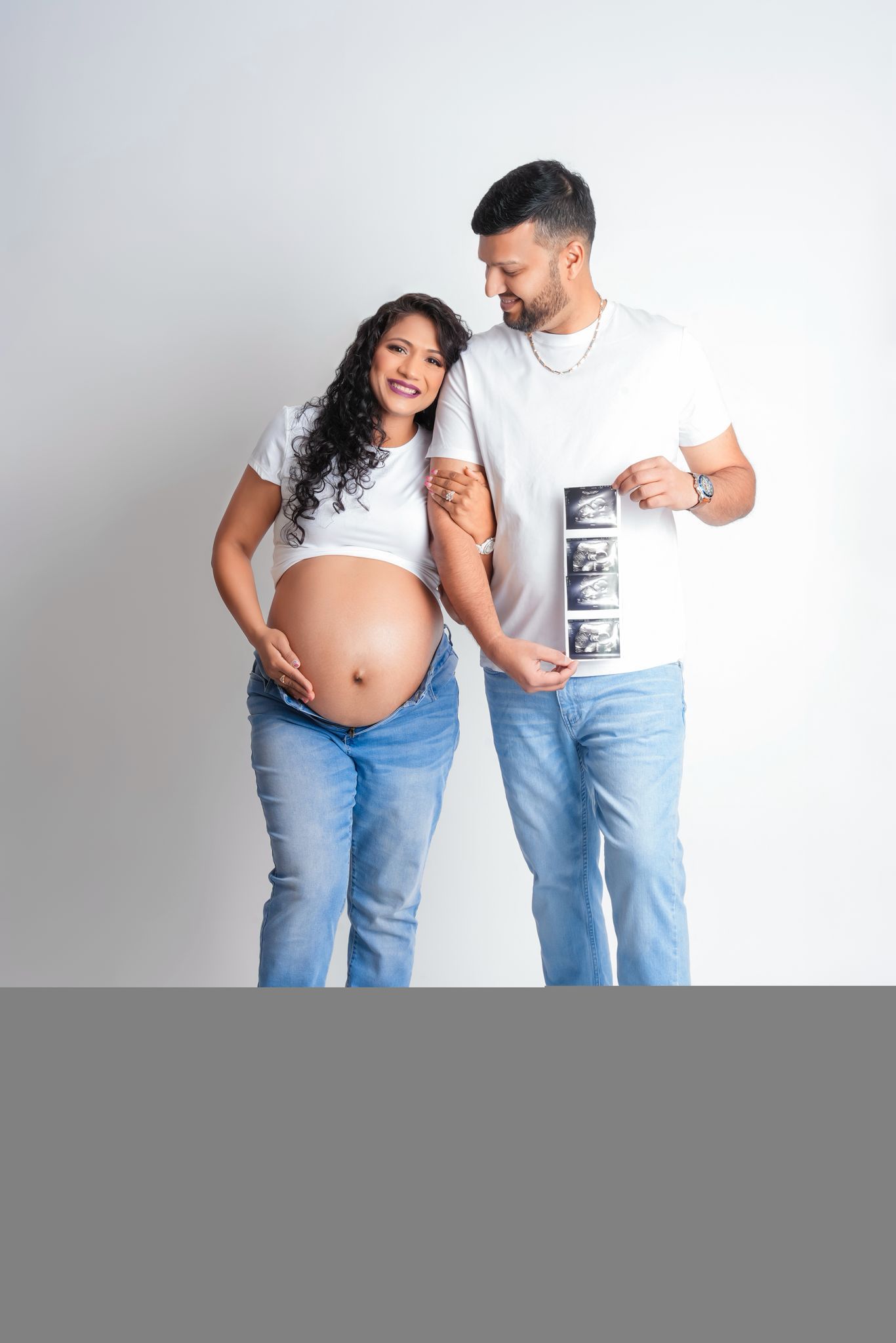 Expectant couple looks at ultrasound photos together during pregnancy photoshoot.