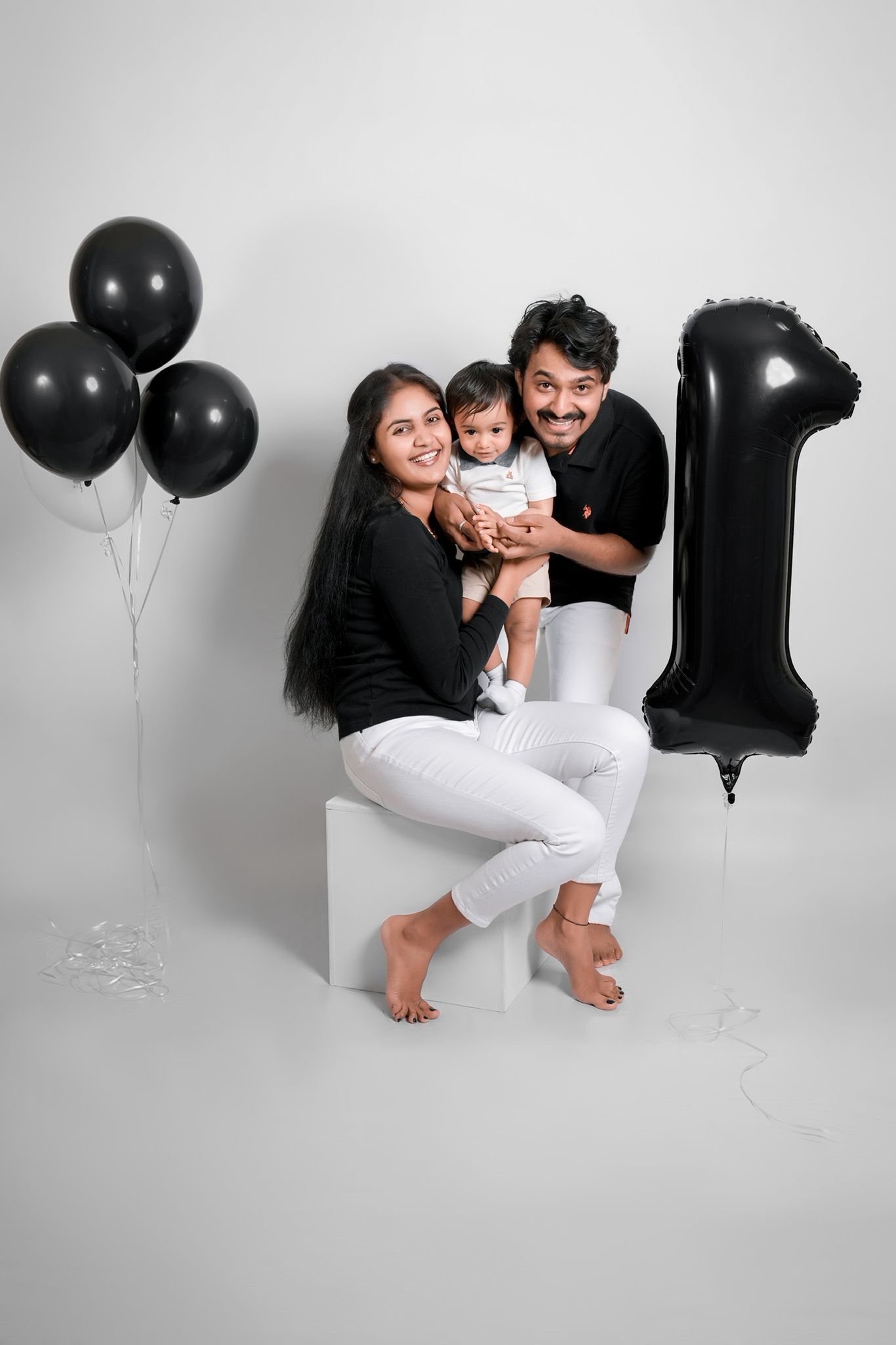 Modern family portrait session with black and white styling and balloon decorations.