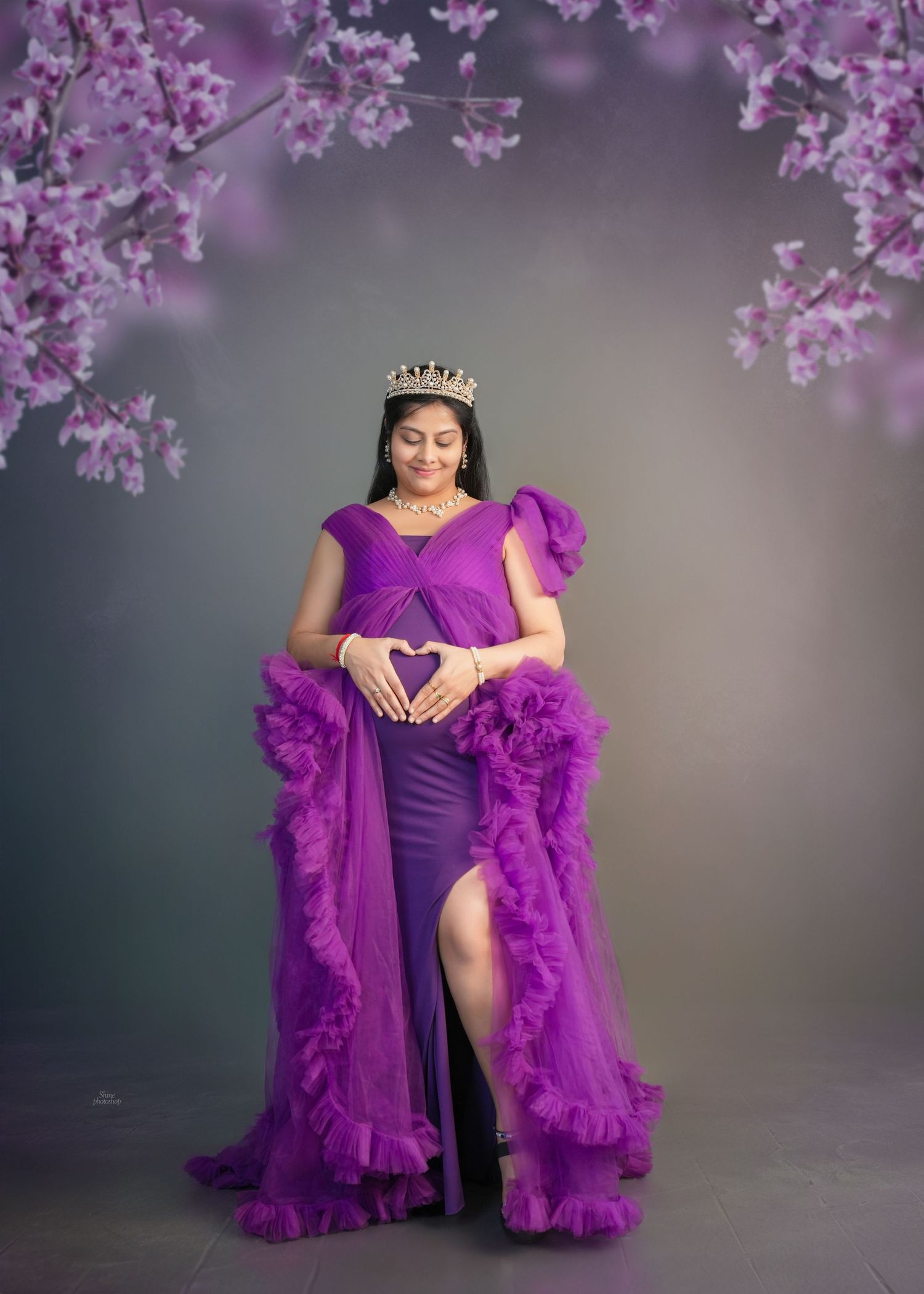 Romantic maternity photos with purple gown under blooming cherry blossoms.