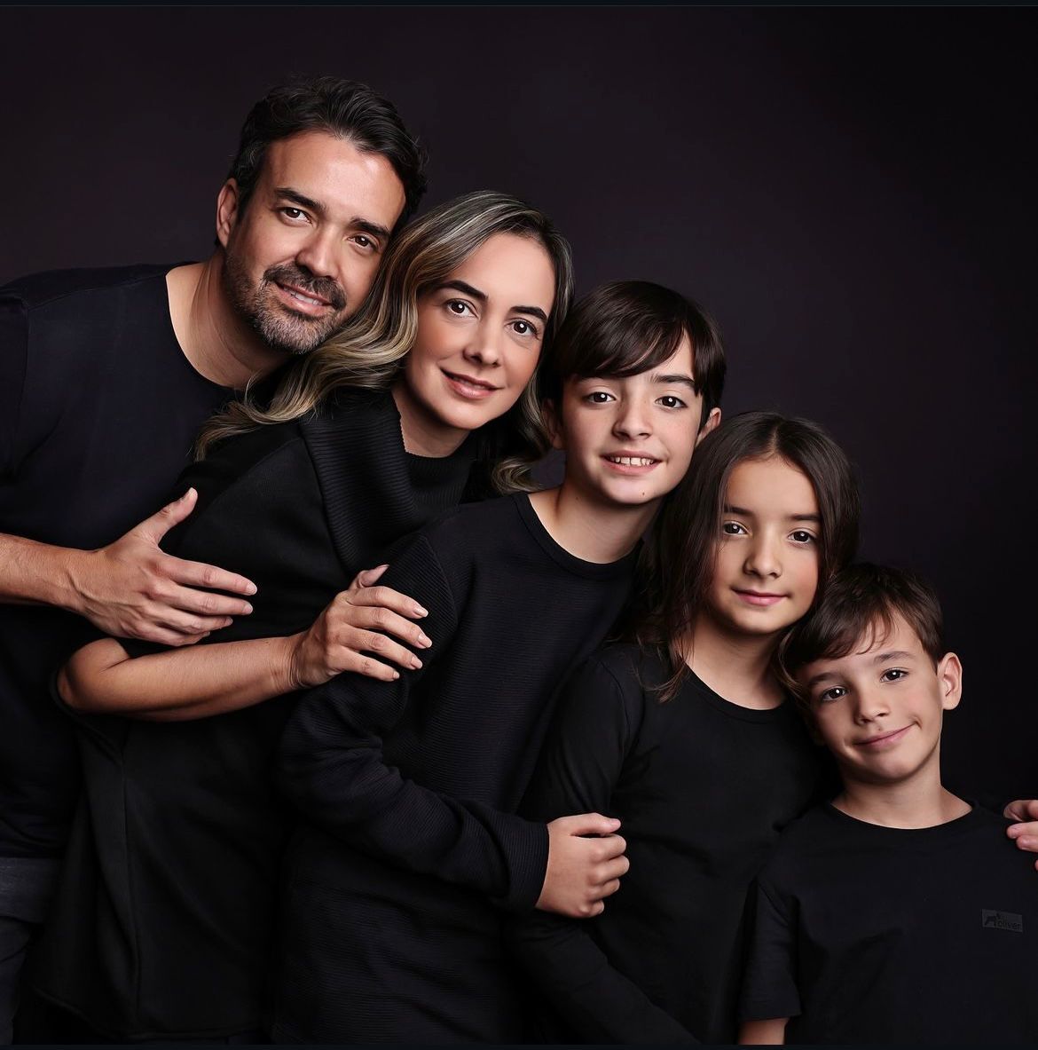 Dark and moody family portrait with everyone in black attire.