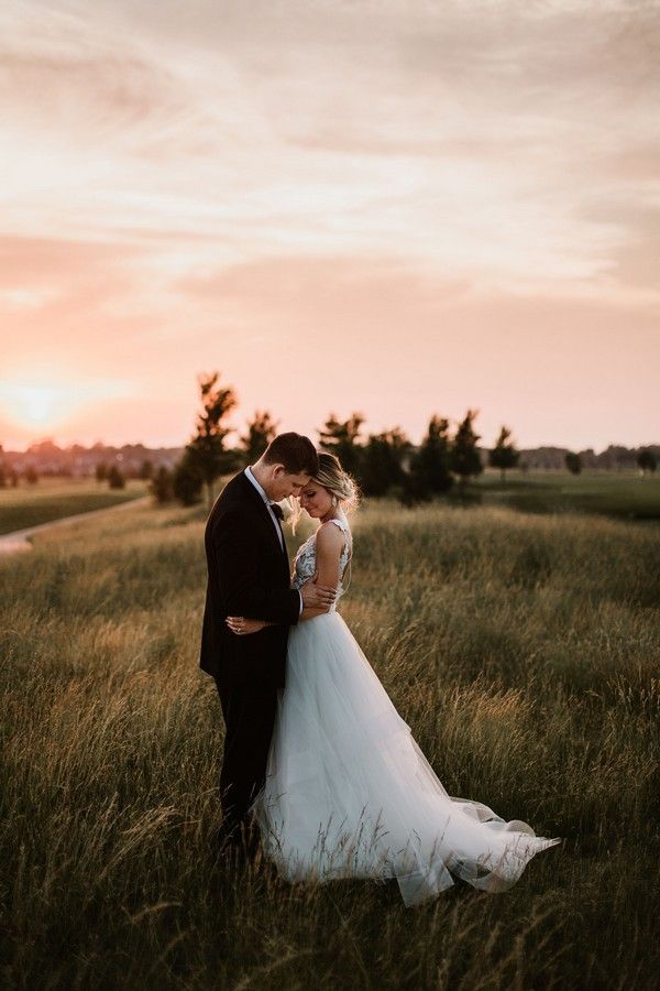 Romantic sunset photoshoot in tall grass field with dramatic sky.
