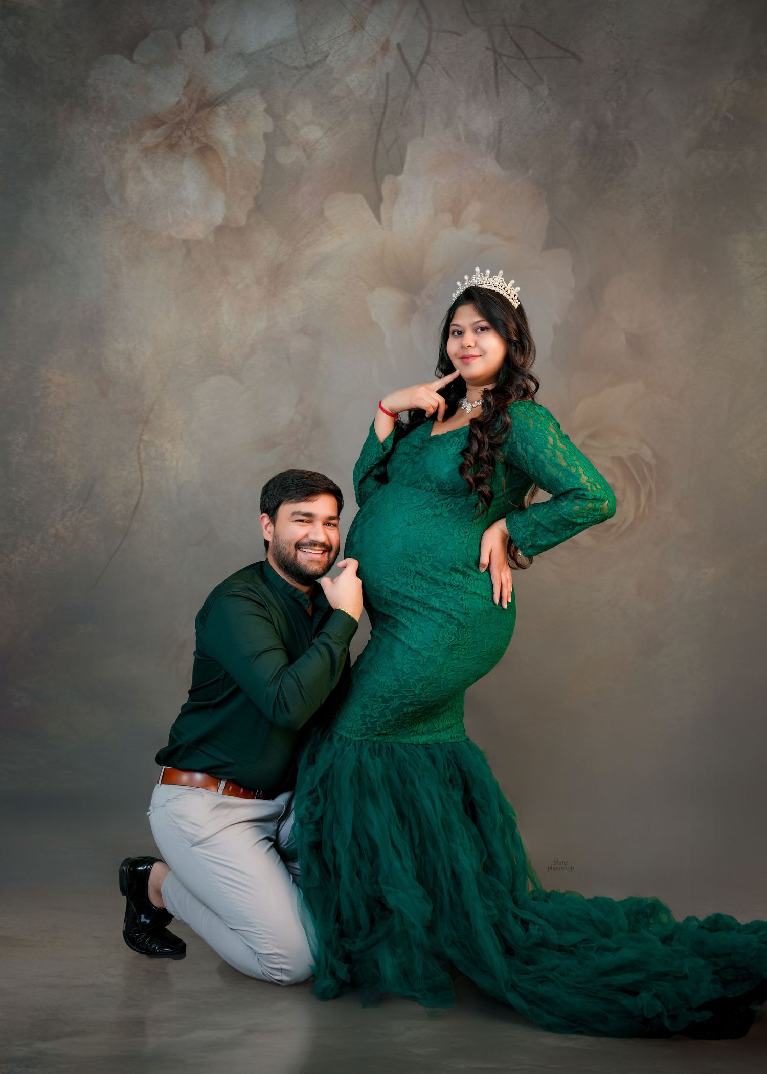 Maternity portrait with dramatic emerald mermaid gown against textured background.