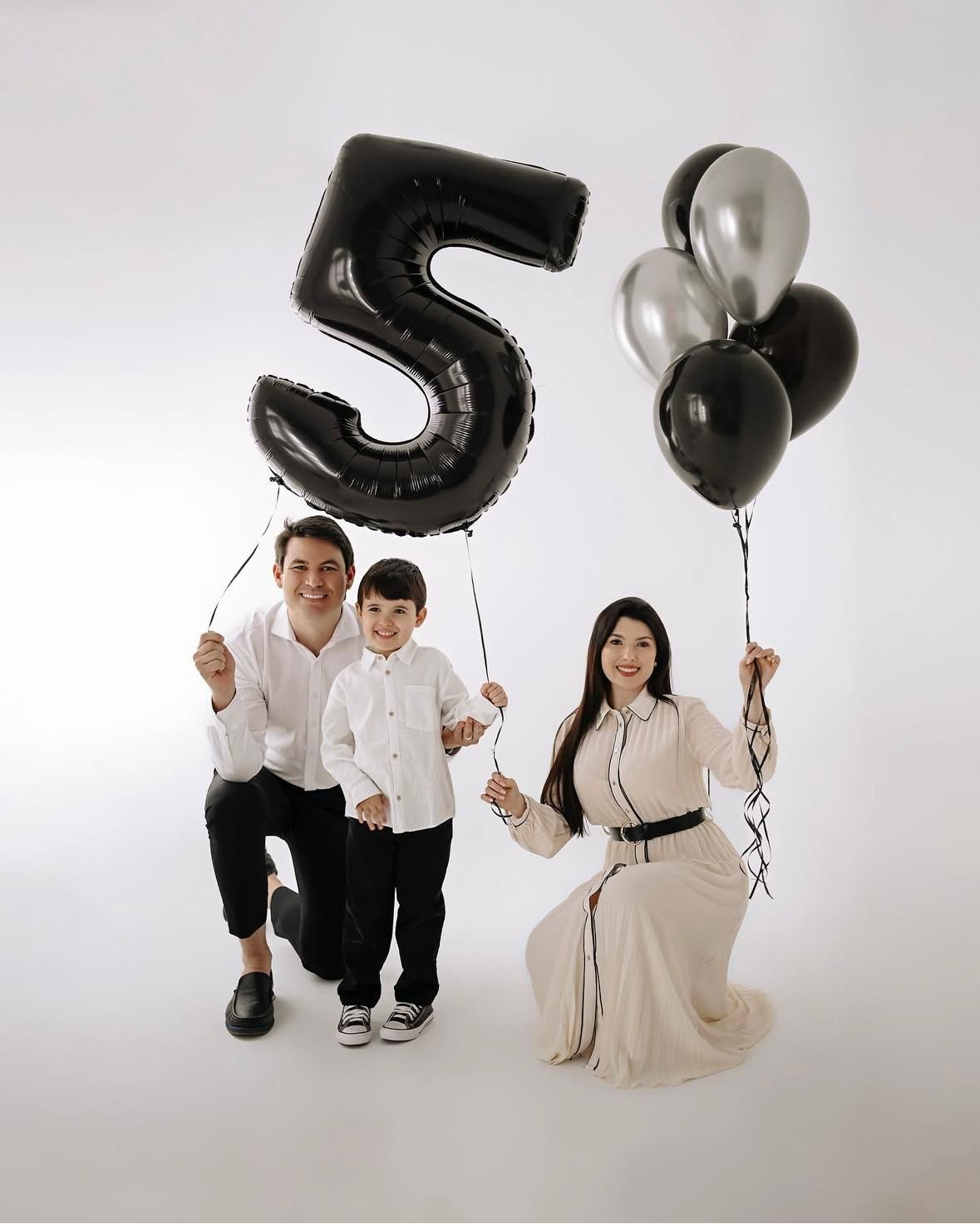 Family portrait session with black and silver number balloons against white backdrop.