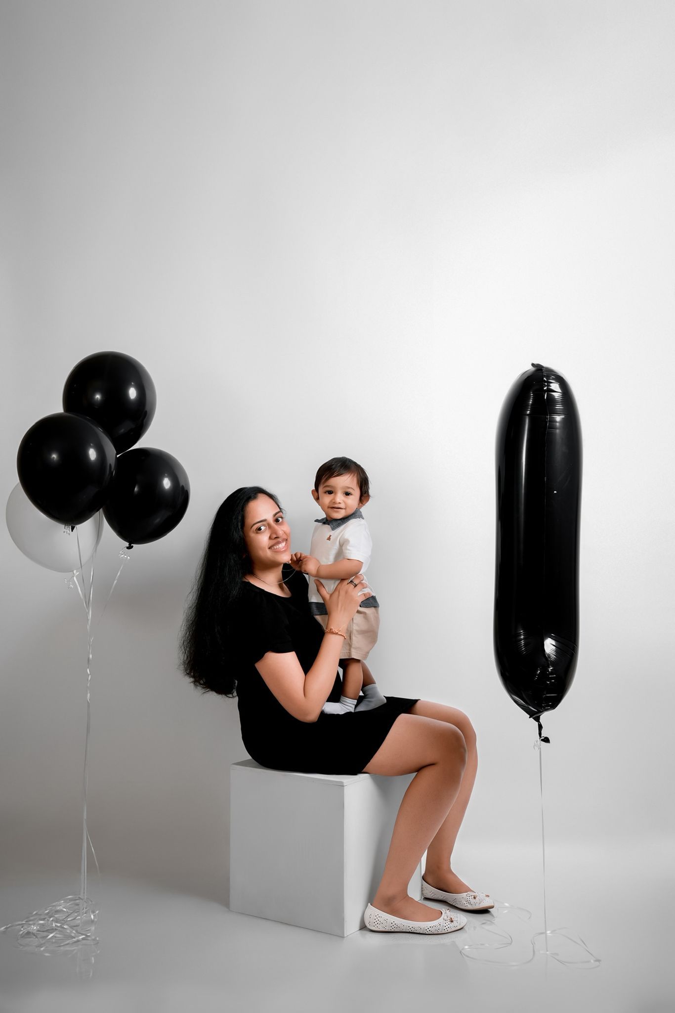 Modern studio portraits with black and white balloon accents and geometric block props.