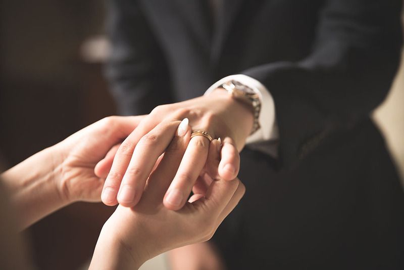Close-up shot of hands exchanging wedding rings during a marriage ceremony.