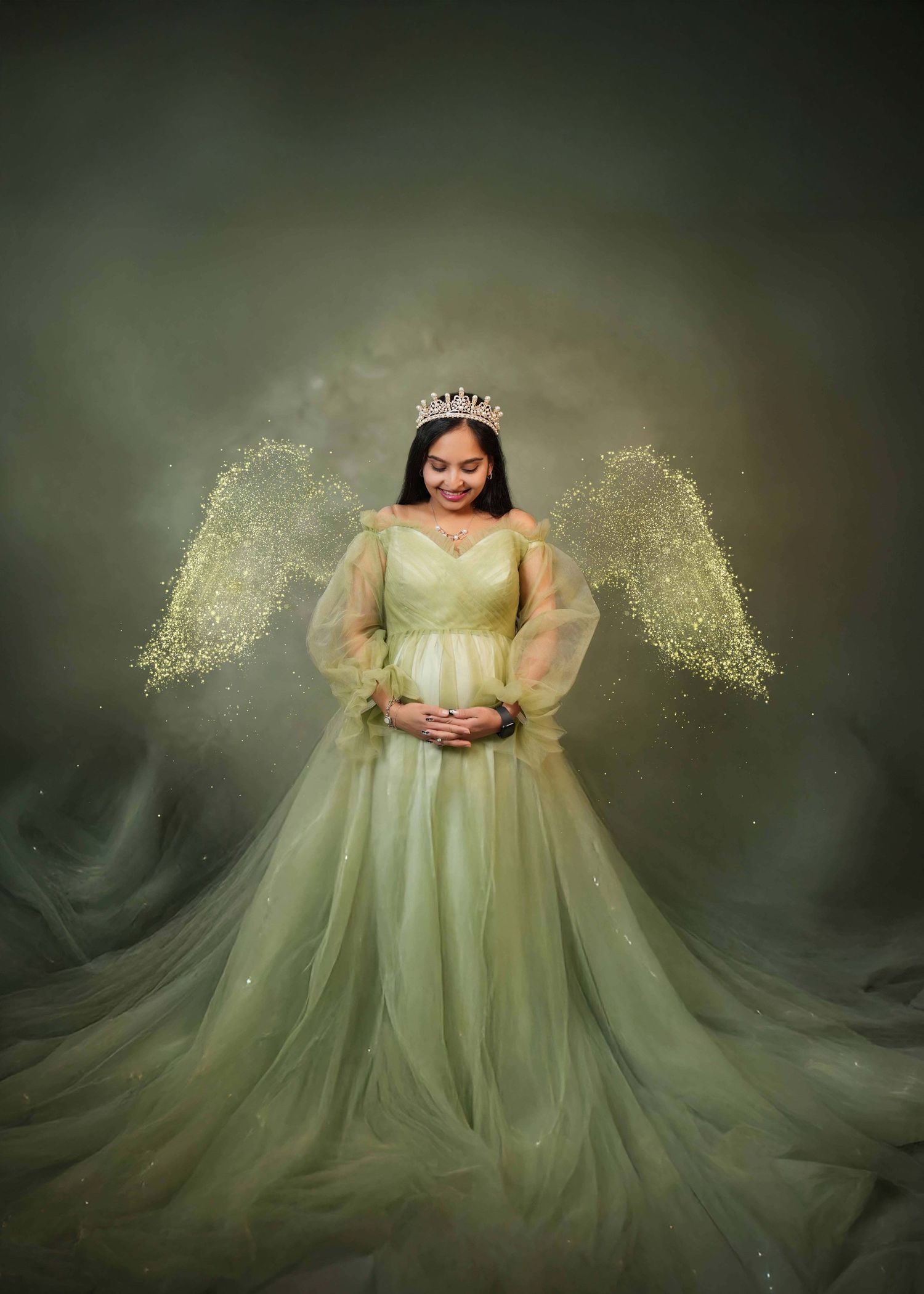 Ethereal maternity portrait with glowing green dress and sparkles against dark background.