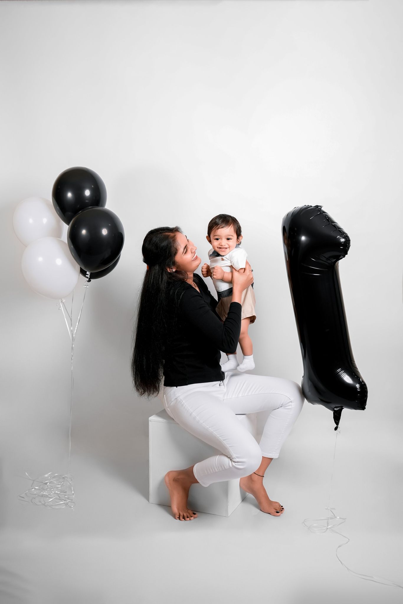 Minimalist family photoshoot with balloon decorations and white cube prop.