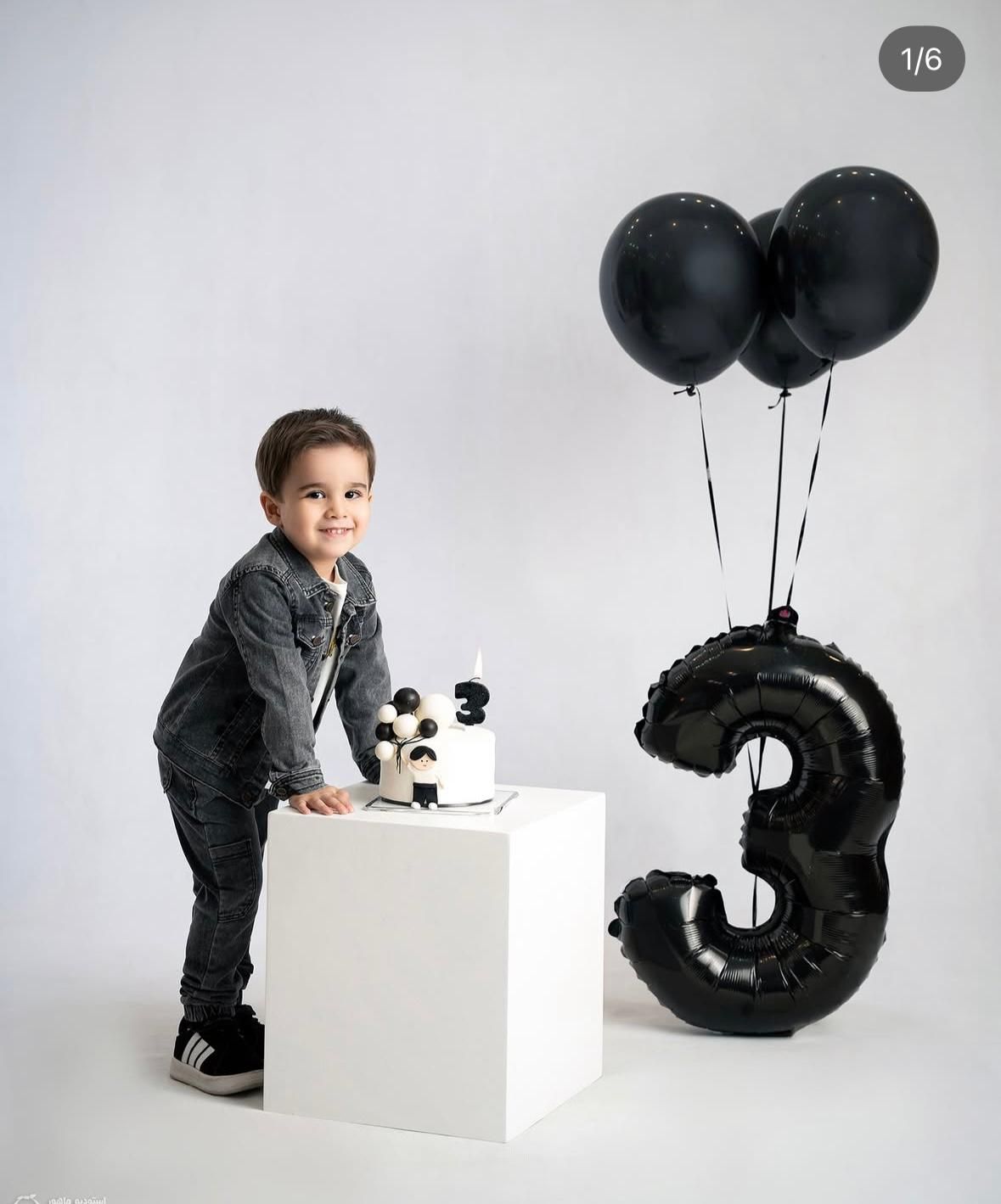 Black and white birthday theme photoshoot with number balloon and cake.