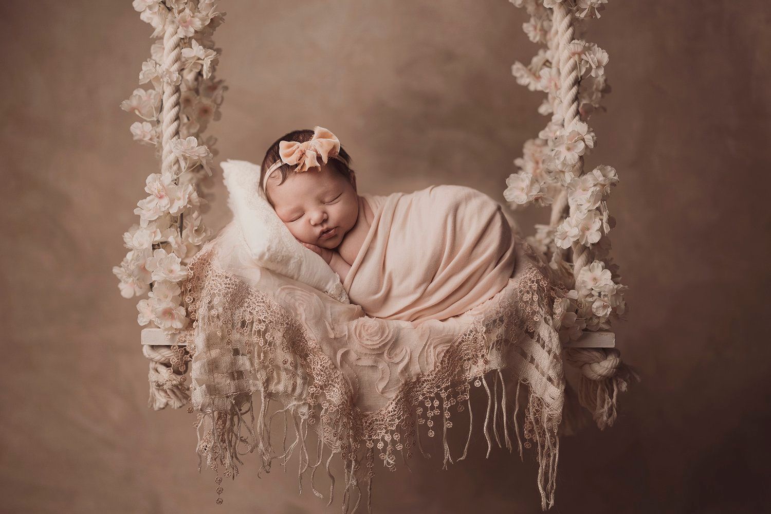 Artistic newborn portrait series with delicate white floral decorations.