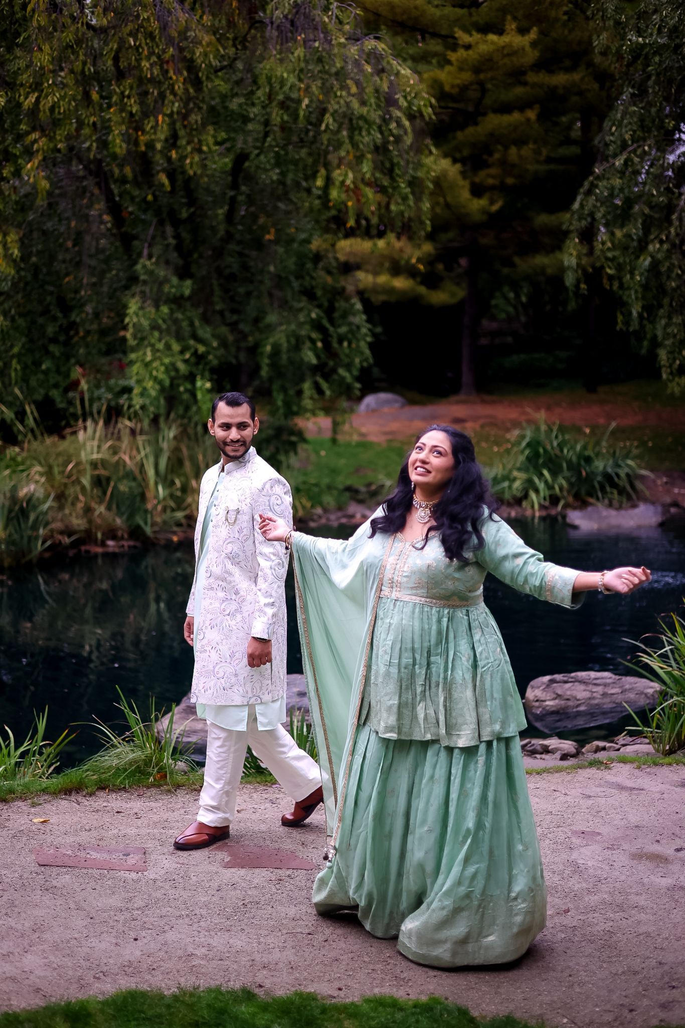 Couple in coordinating mint green dress and floral print shirt posing playfully outdoors.