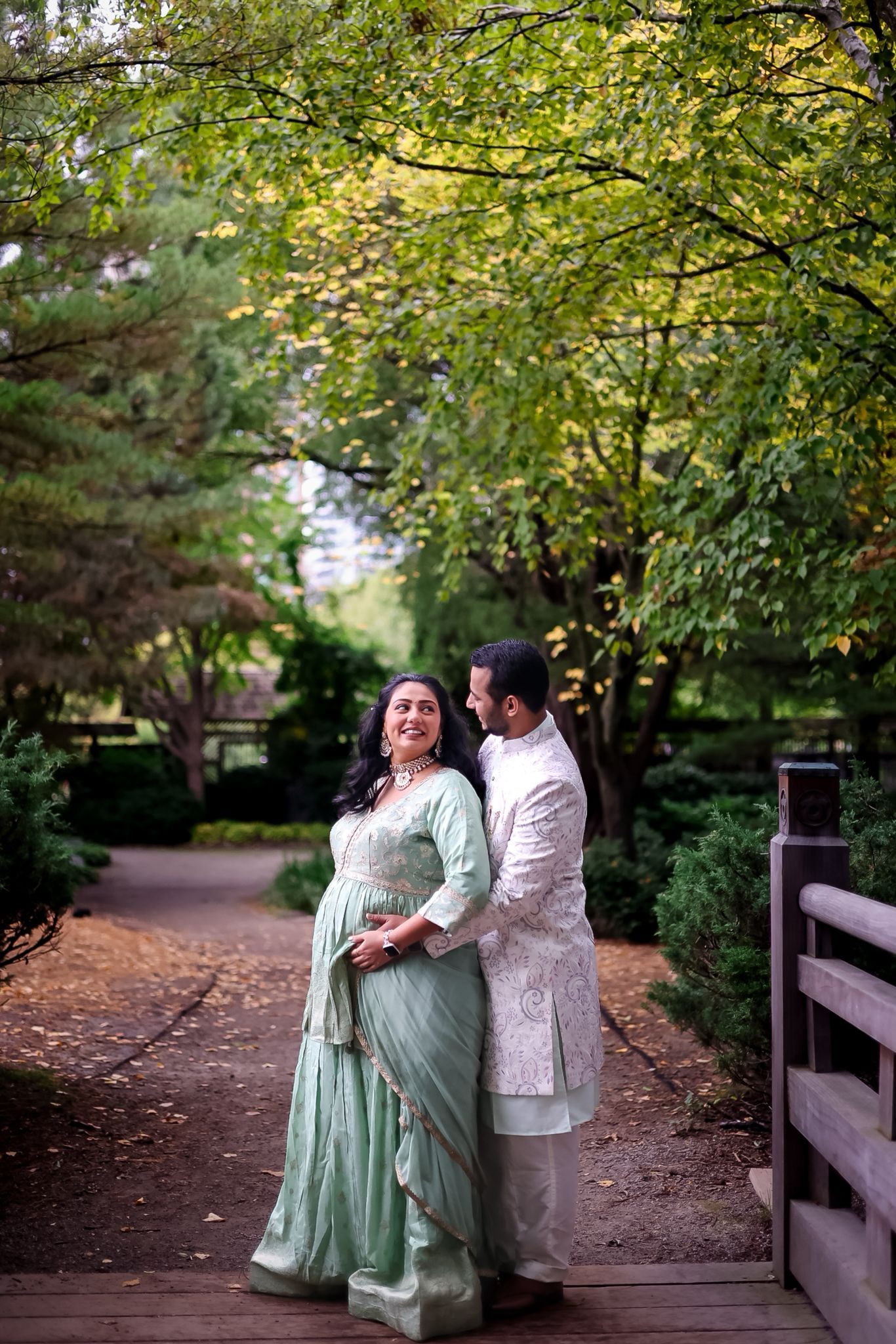 A couple in traditional attire walks along a tree-lined path during autumn.