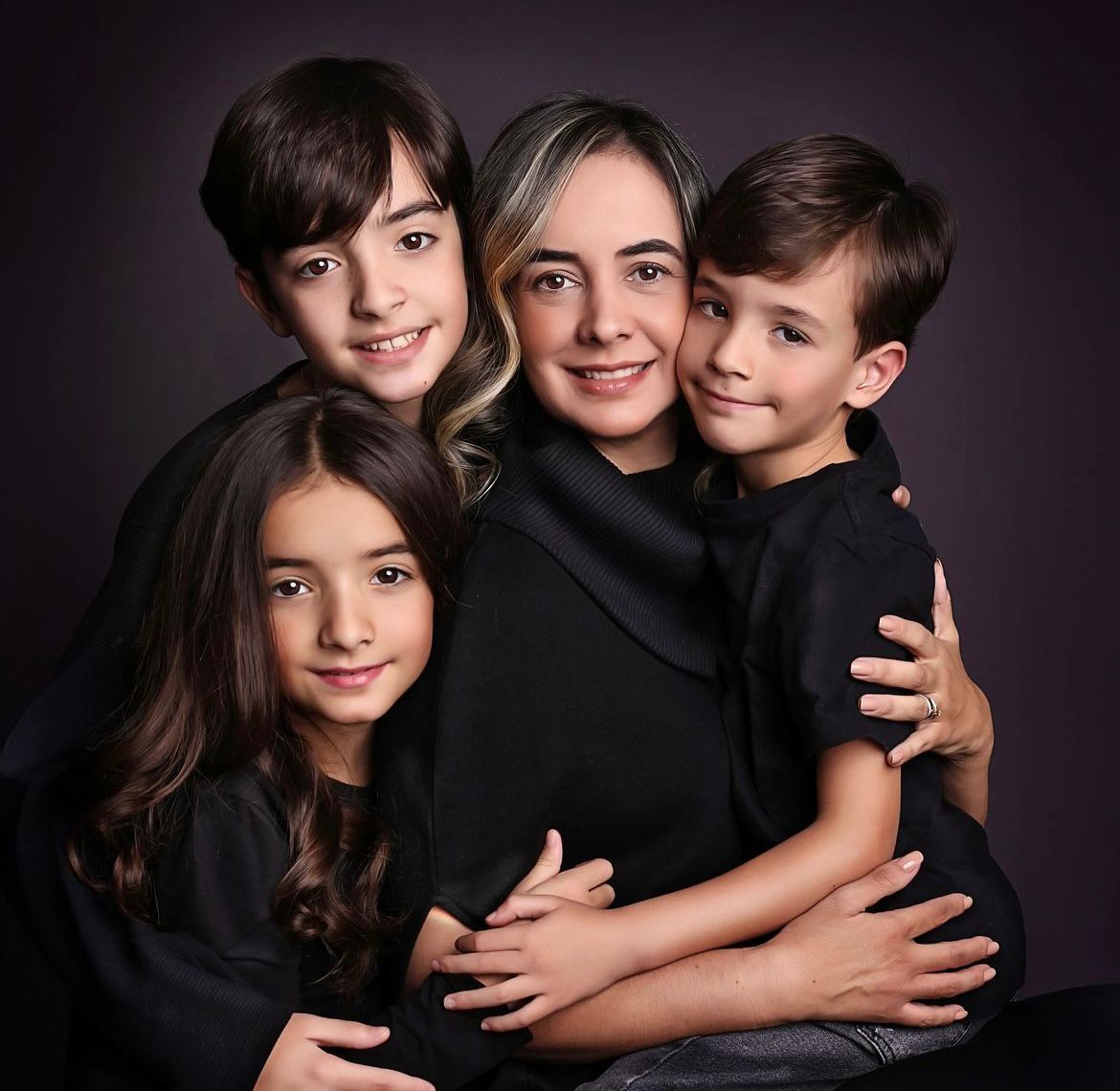 Intimate family photo session with dark clothing against black background.