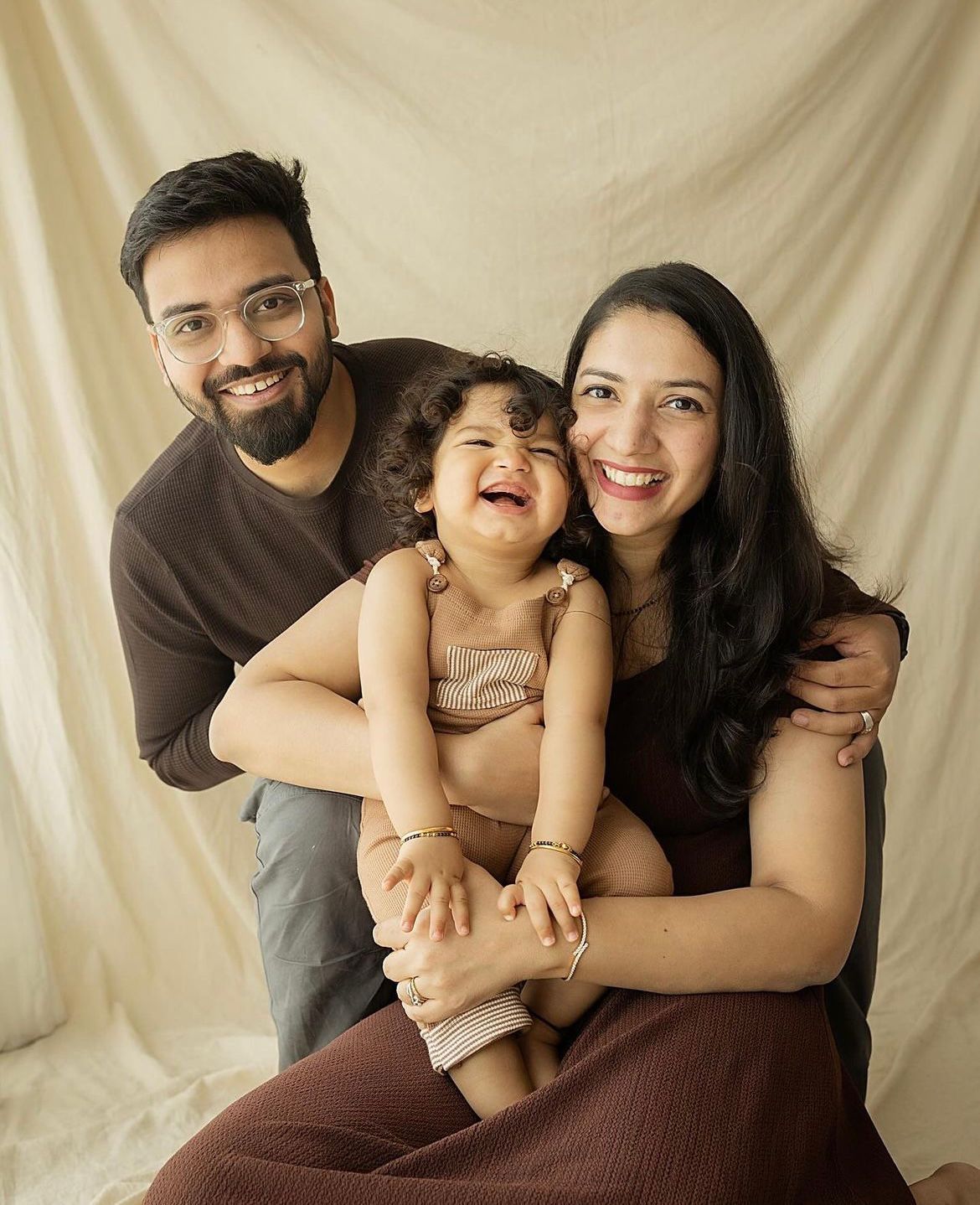 Joyful family portraits showing natural interactions on beige backdrop.