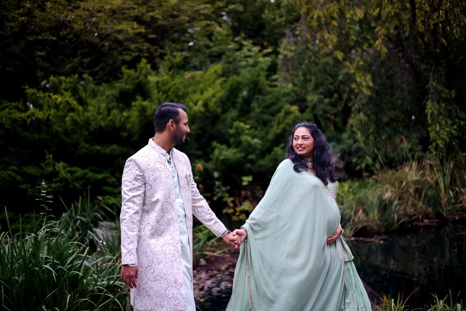 A couple shares romantic moments in coordinated outfits against a natural park backdrop.
