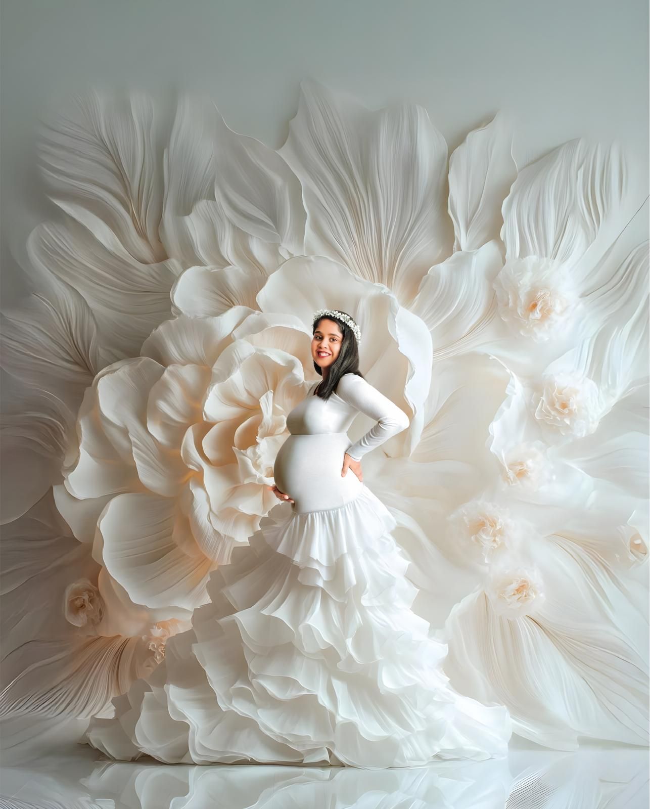 Ethereal white paper flower backdrop creates romantic atmosphere for maternity portrait.