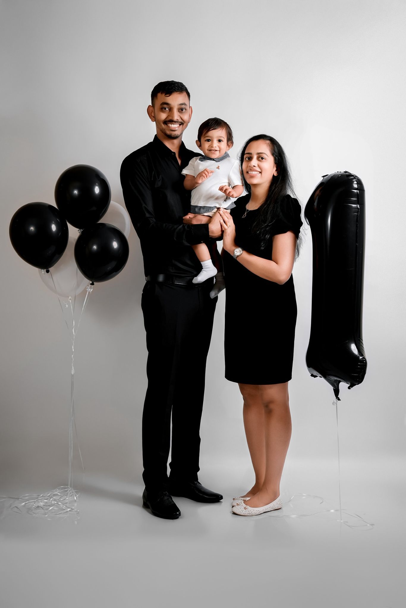 Family photography session with minimalist black and white theme and balloon decorations.