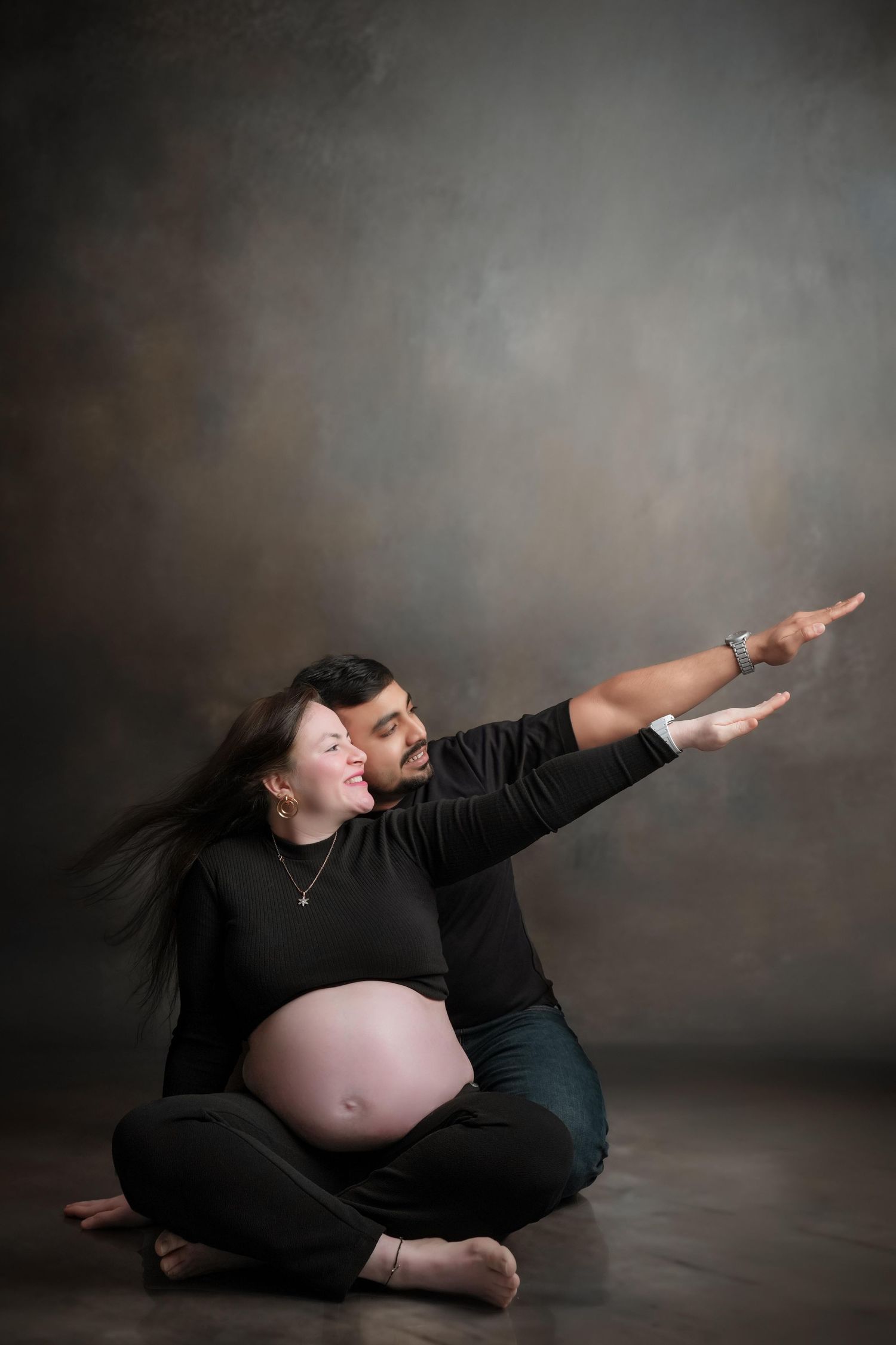 Artistic maternity photos show an expectant mother in black against dark background.