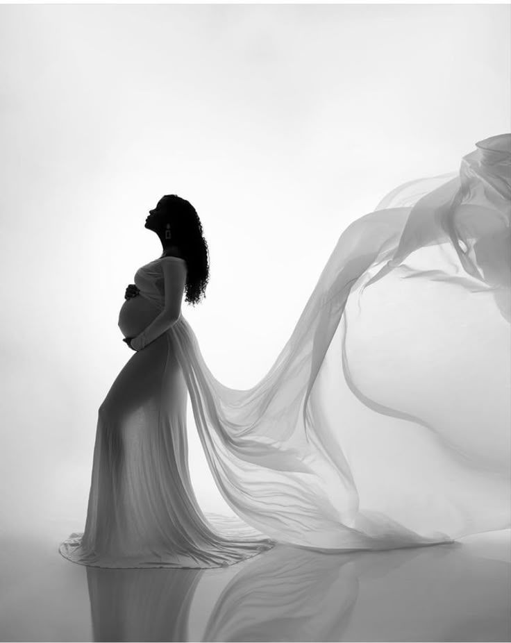 Artistic black and white maternity photos with flowing fabric creating dramatic silhouettes.
