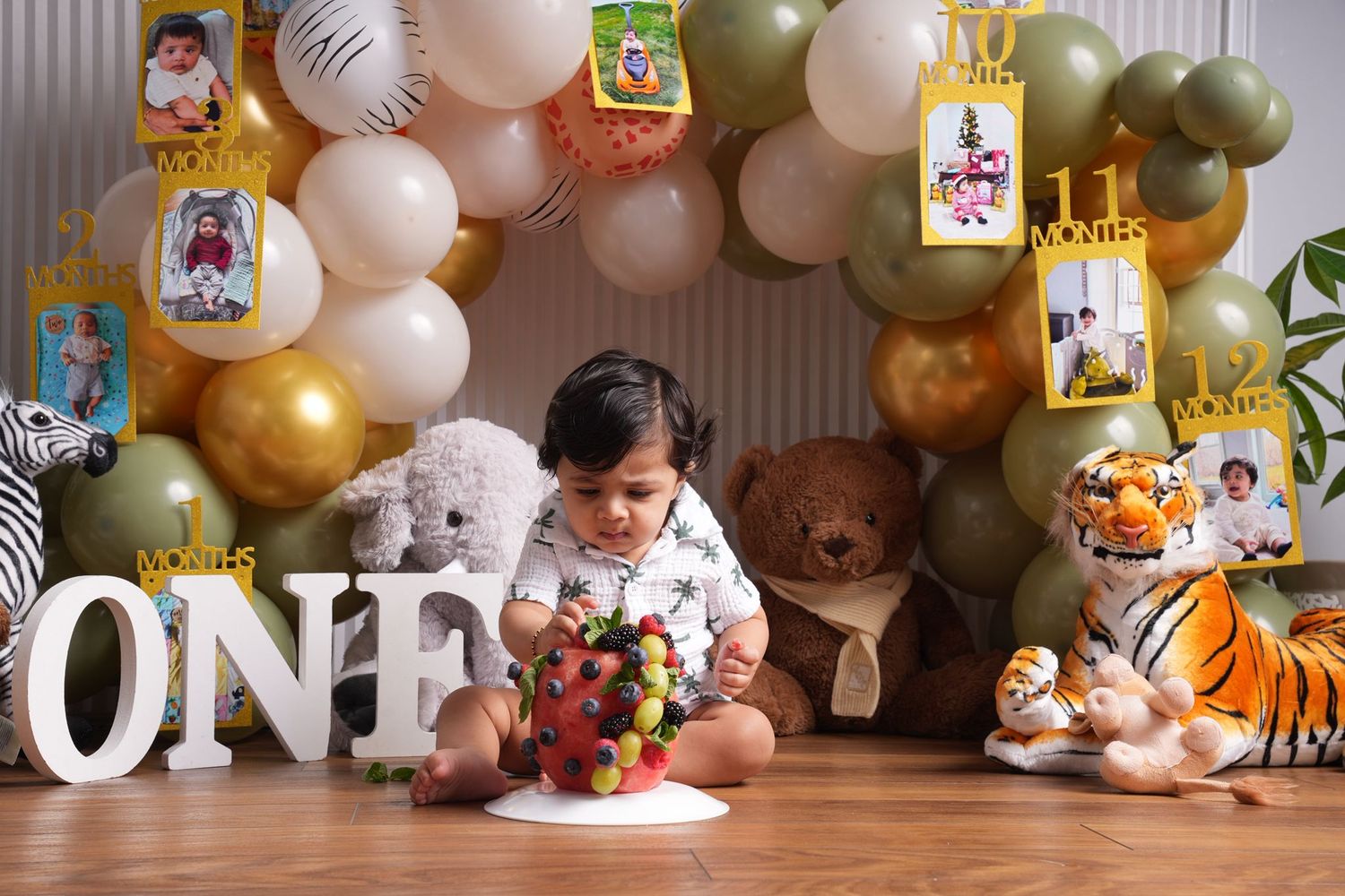 First birthday party setup with balloons, stuffed animals and 'ONE' sign.