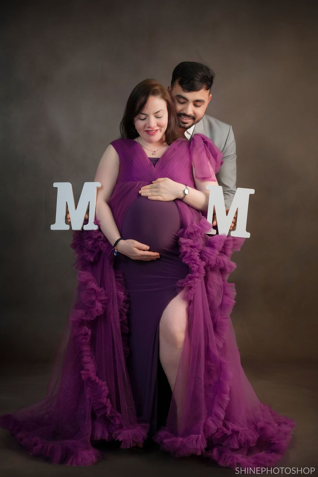 Intimate maternity session with dramatic purple ruffled gown and decorative letter props.