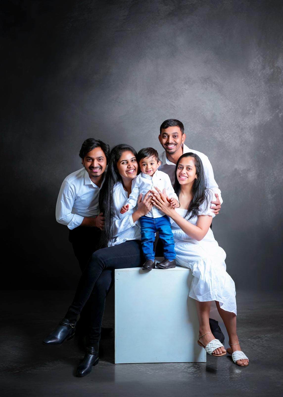 Family portrait session with white cube prop against dark backdrop.