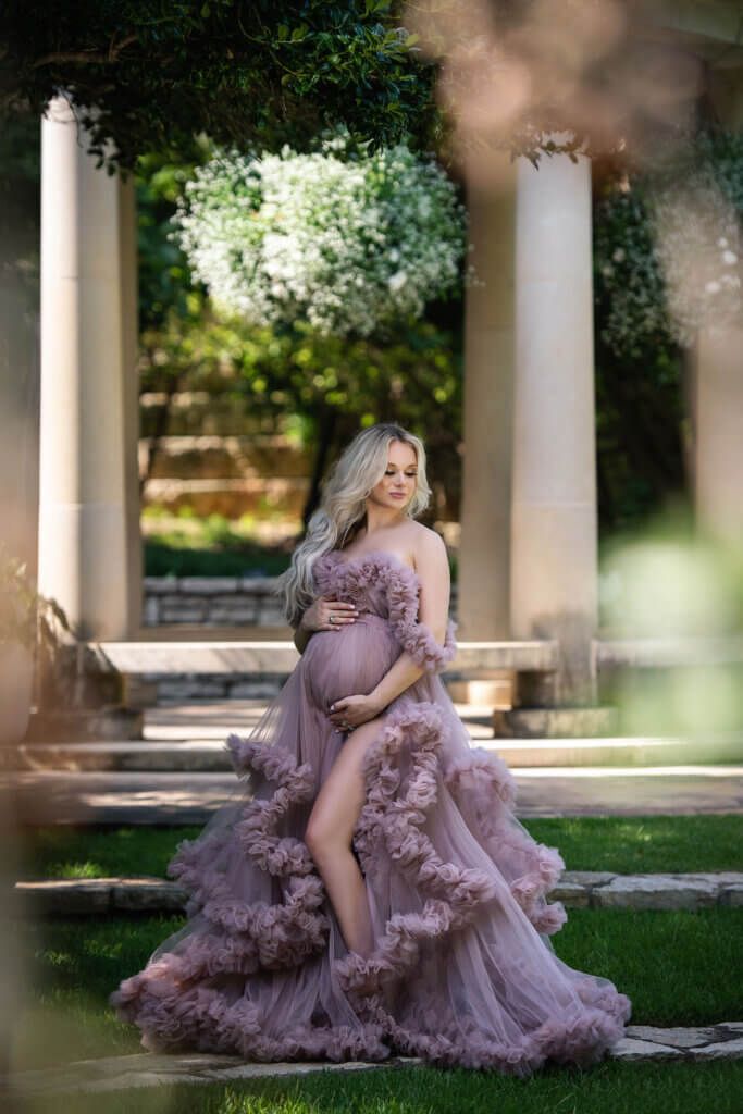 Ethereal maternity portraits in a lavender tulle gown set in an outdoor colonnade.