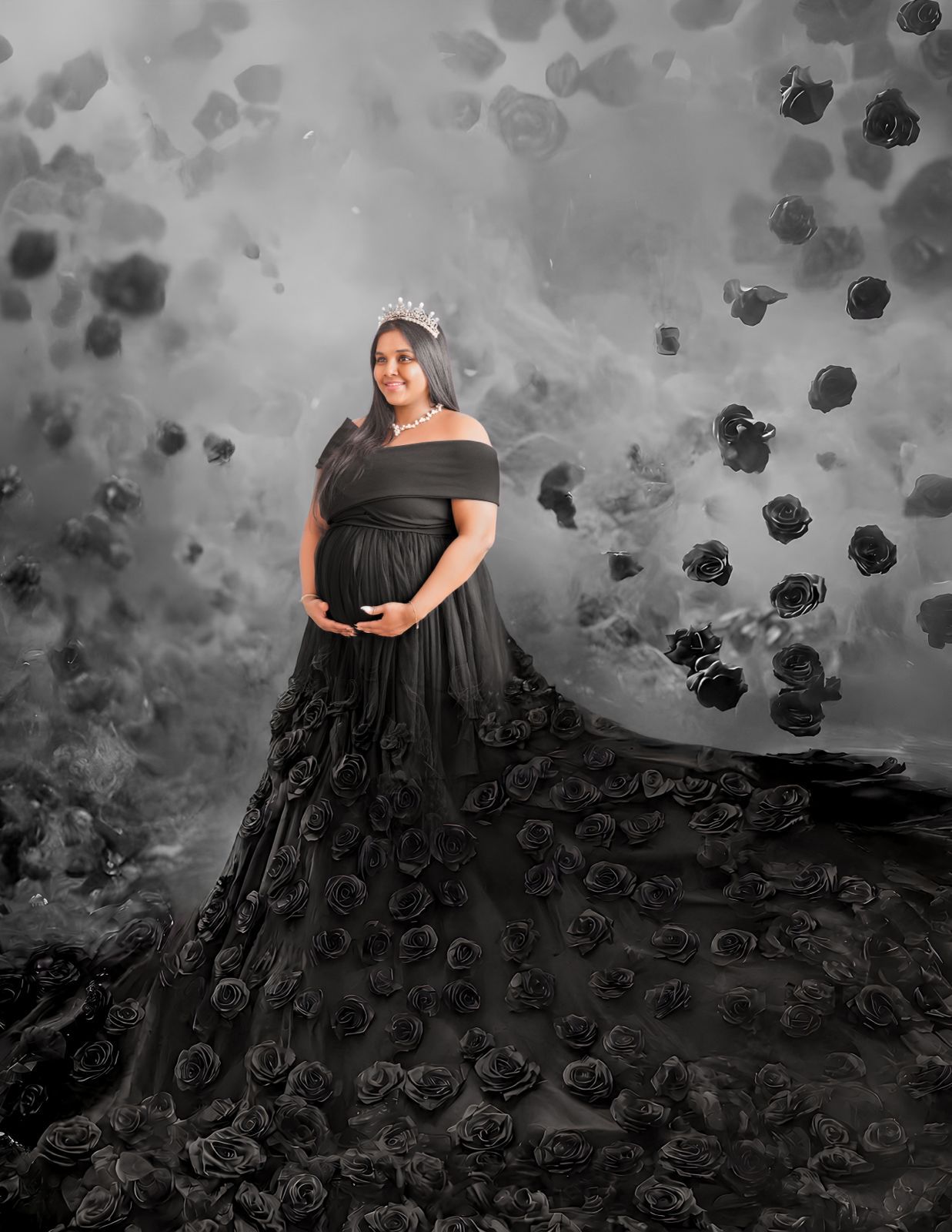 Pregnant woman in black floral gown with crown poses elegantly among falling roses in a dramatic maternity portrait.