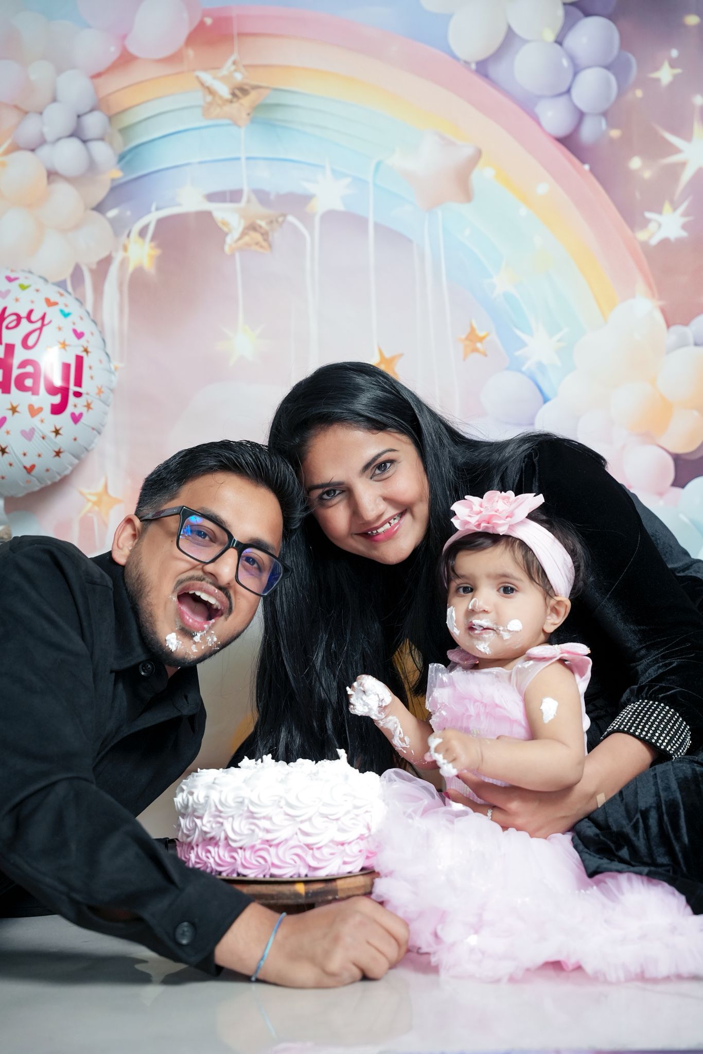 Cake smash photo session with pastel rainbow backdrop and whimsical decorations.