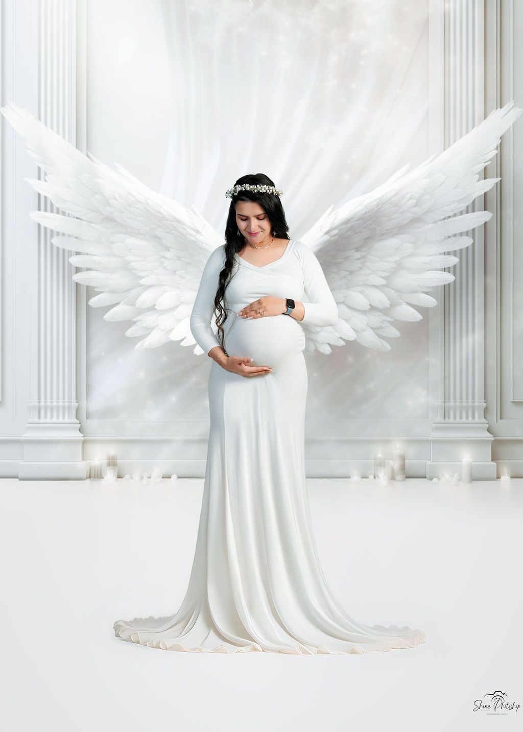 Maternity portrait featuring white gown and angel wings against classical pillared backdrop.