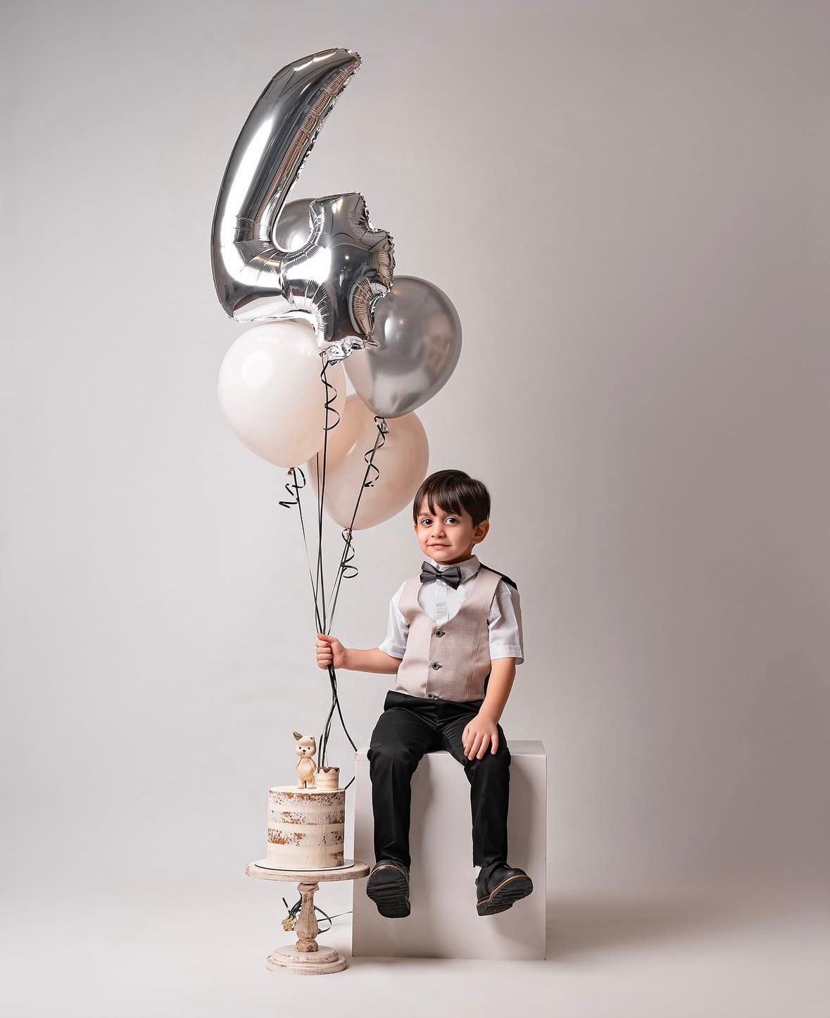 Silver and black balloon decorations with white cake for birthday celebration.