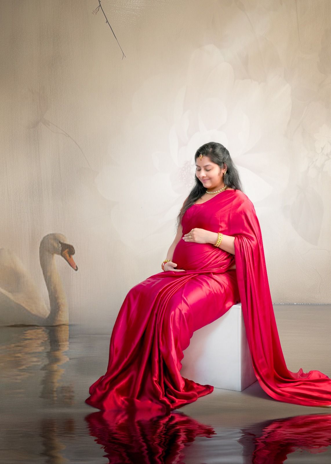 A dramatic maternity photoshoot featuring flowing red fabric and elegant poses against a neutral backdrop.