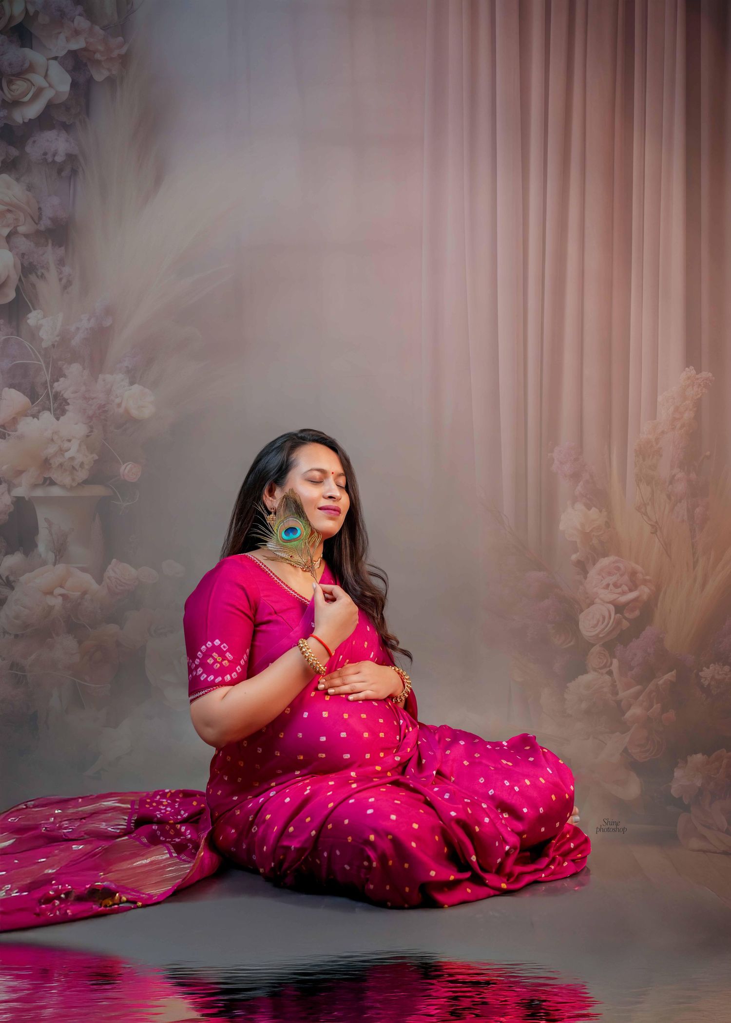 Maternity photoshoot featuring a flowing hot pink dress against a floral backdrop.
