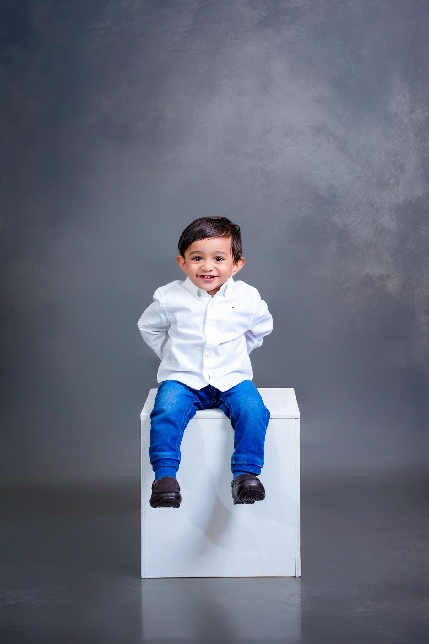 Studio portrait series on white bench against grey backdrop.