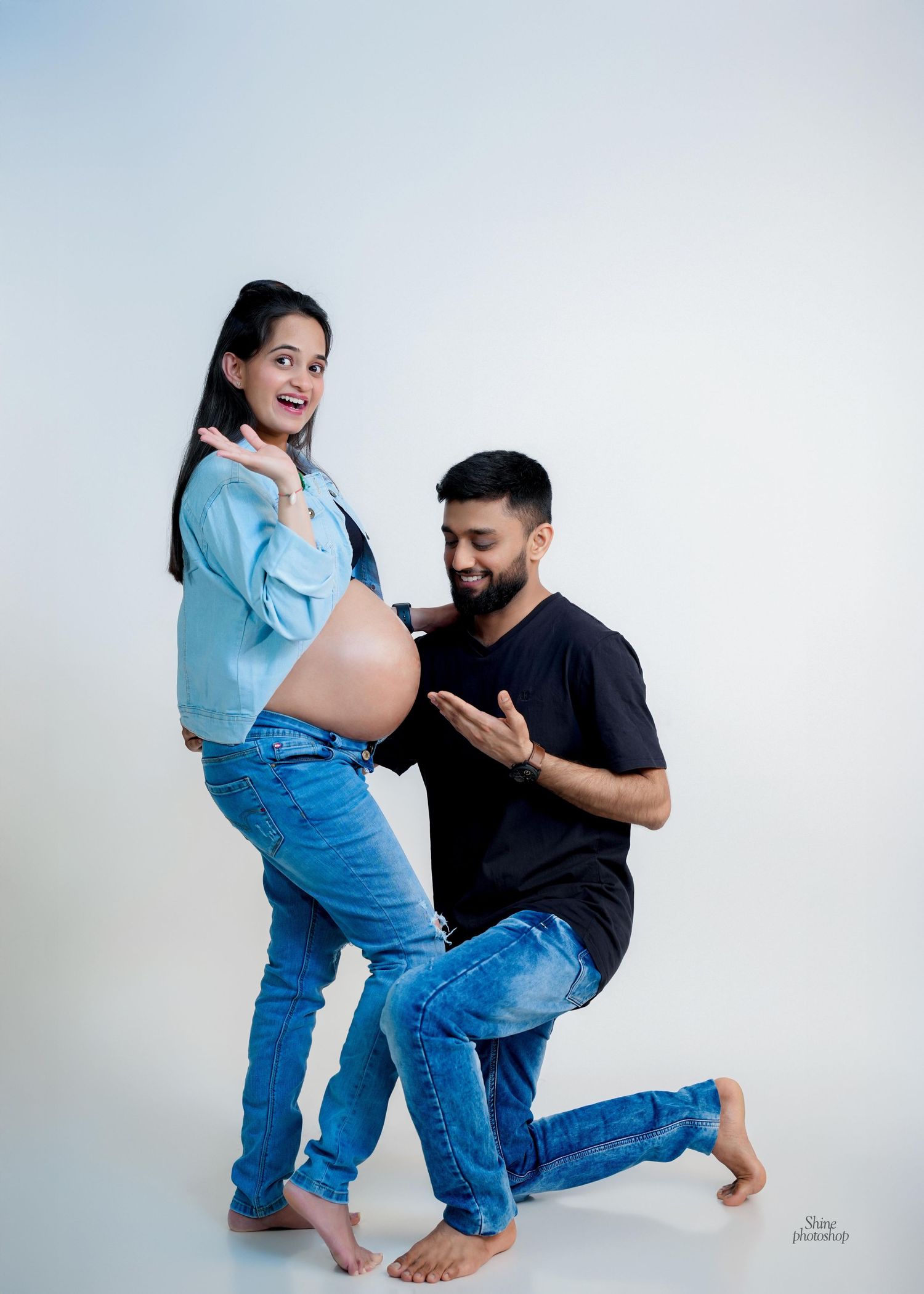 Playful pregnancy announcement photoshoot with couple in casual denim outfits.