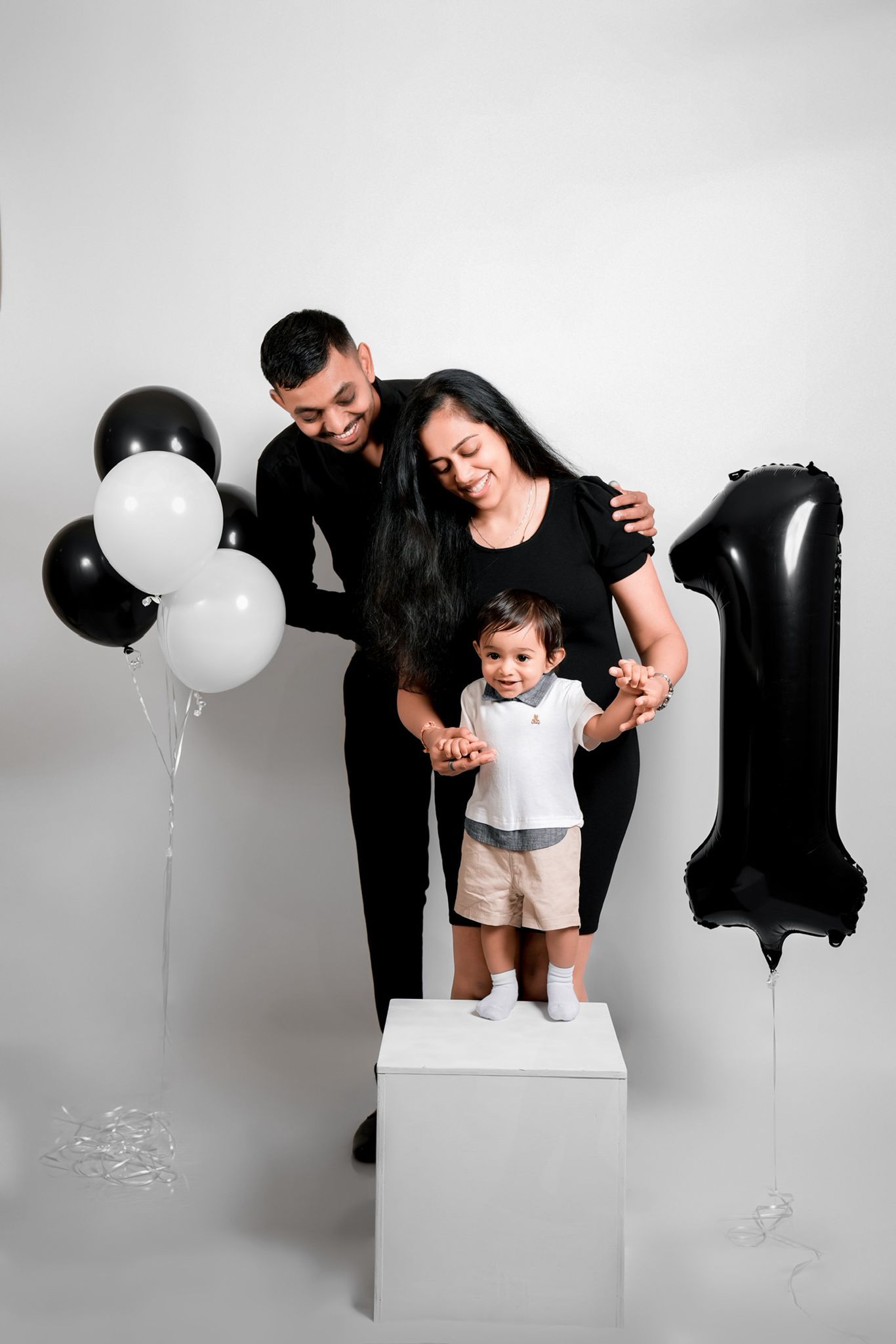 Family photo session with black and white balloons against white backdrop showing playful poses on blocks.