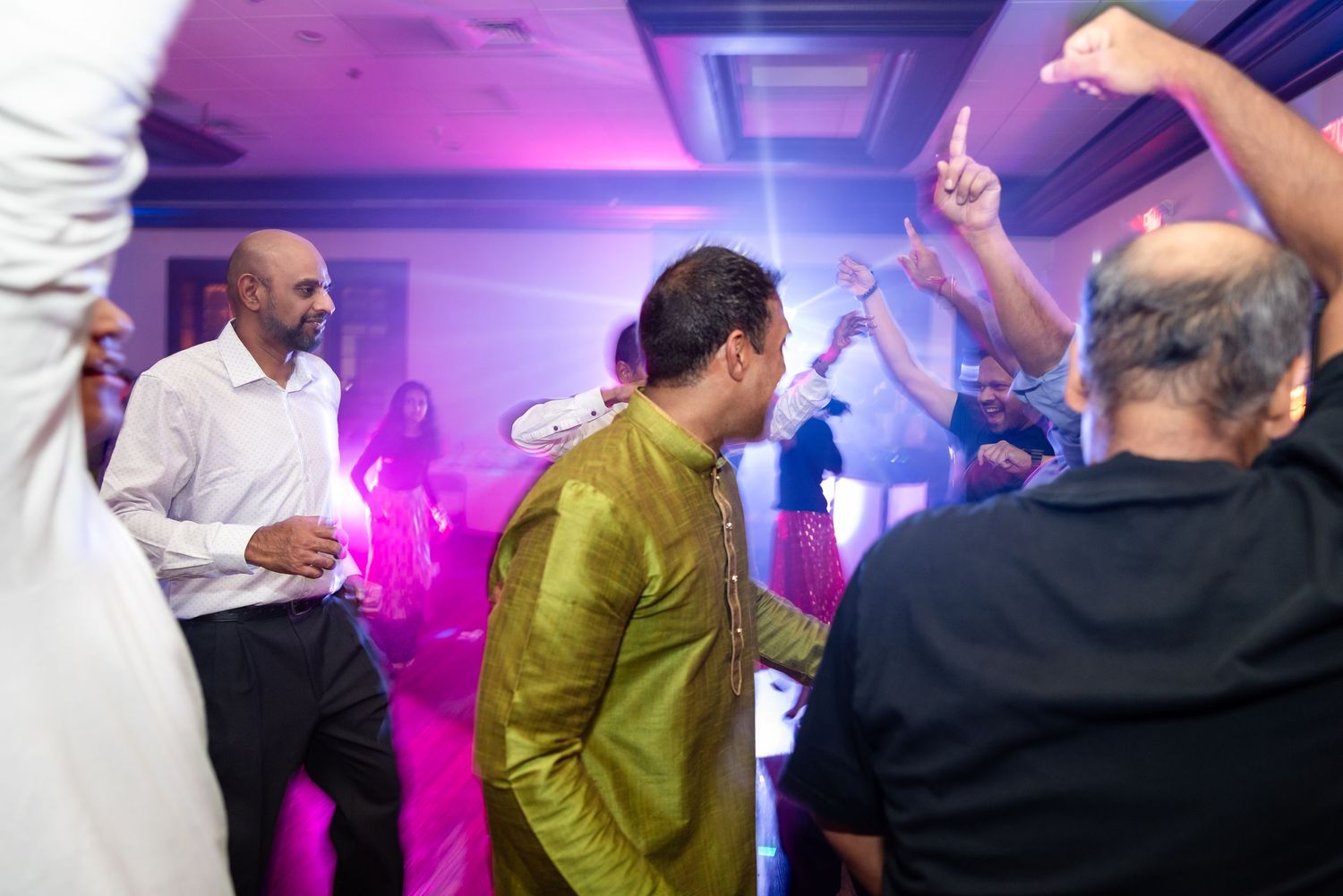 People dancing in a purple-lit room during a festive celebration.