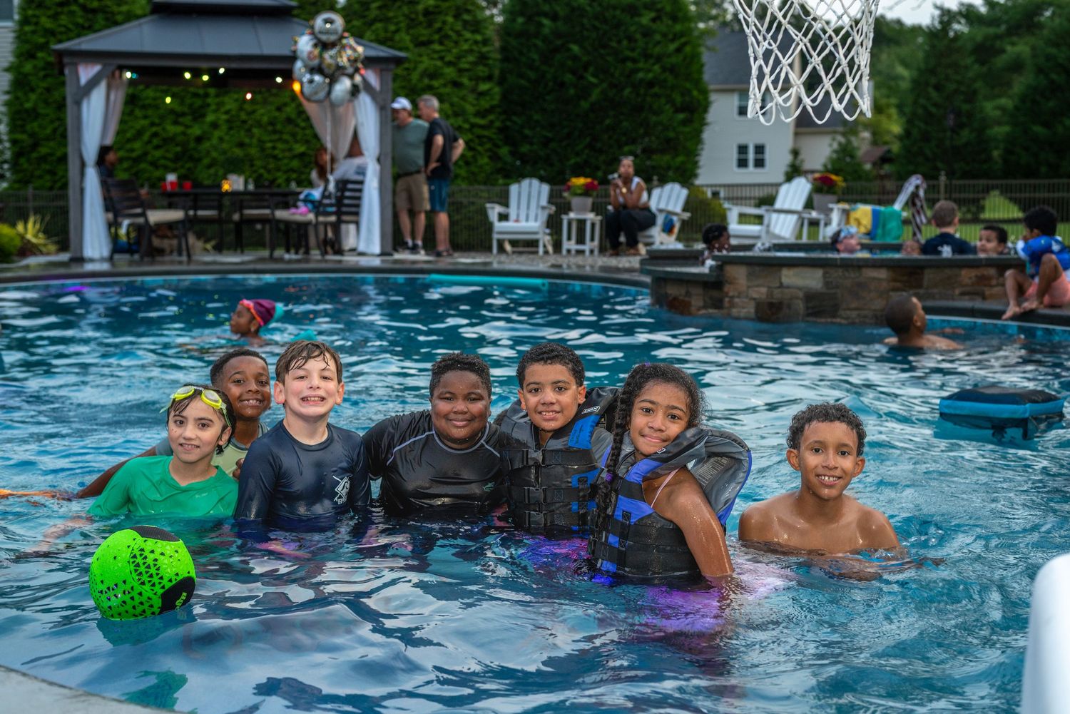 People enjoying a summer pool party with colorful decorations and activities.